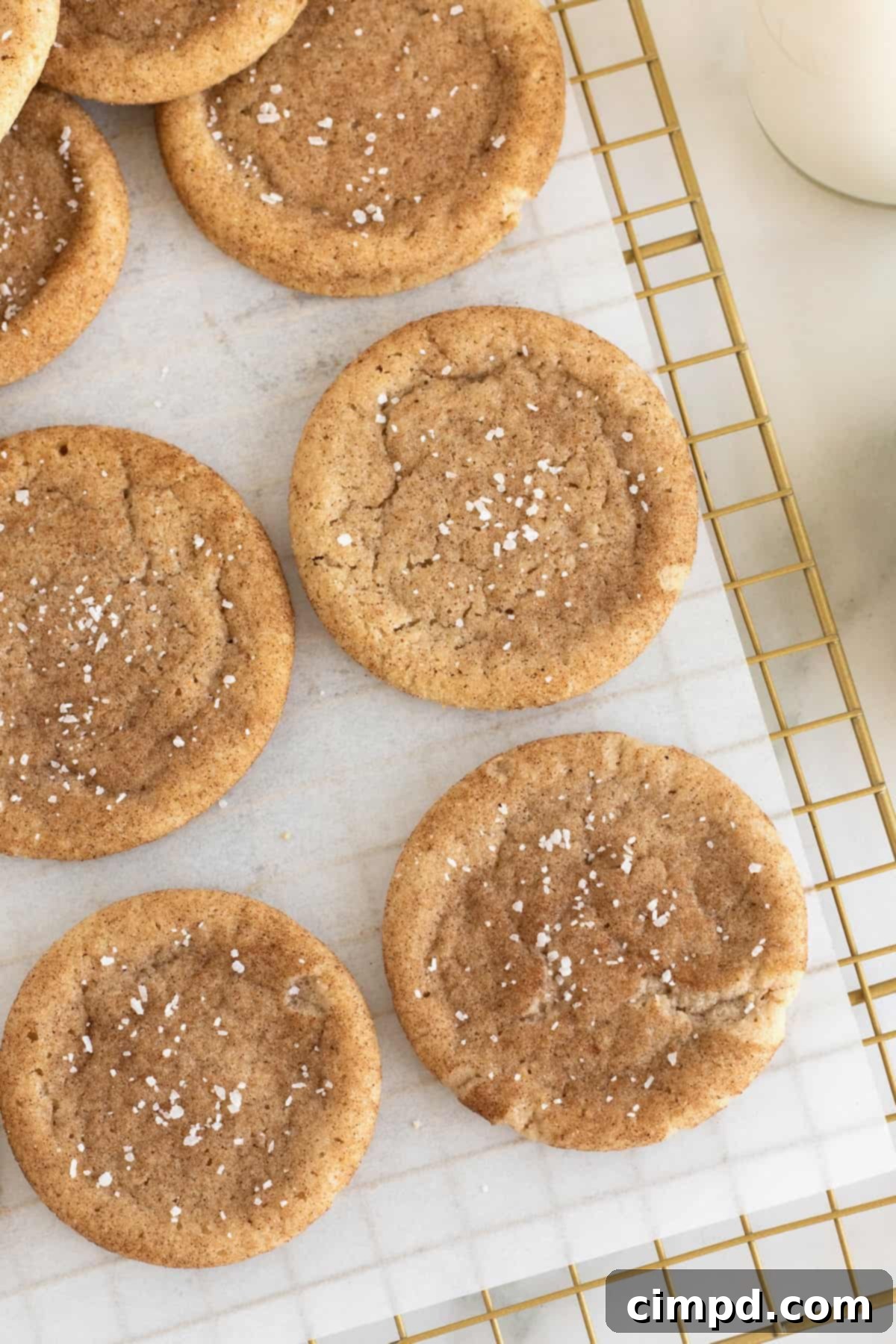 Brown Butter Snickerdoodle cookies sprinkled with sea salt on a parchment lined cooling rack.