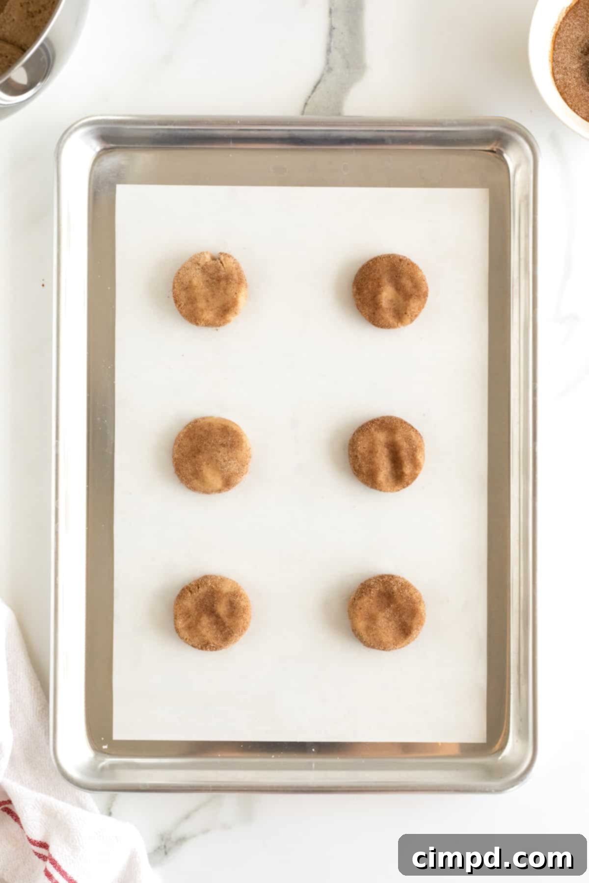 Snickerdoodle cookie balls pressed down on a cookie sheet.