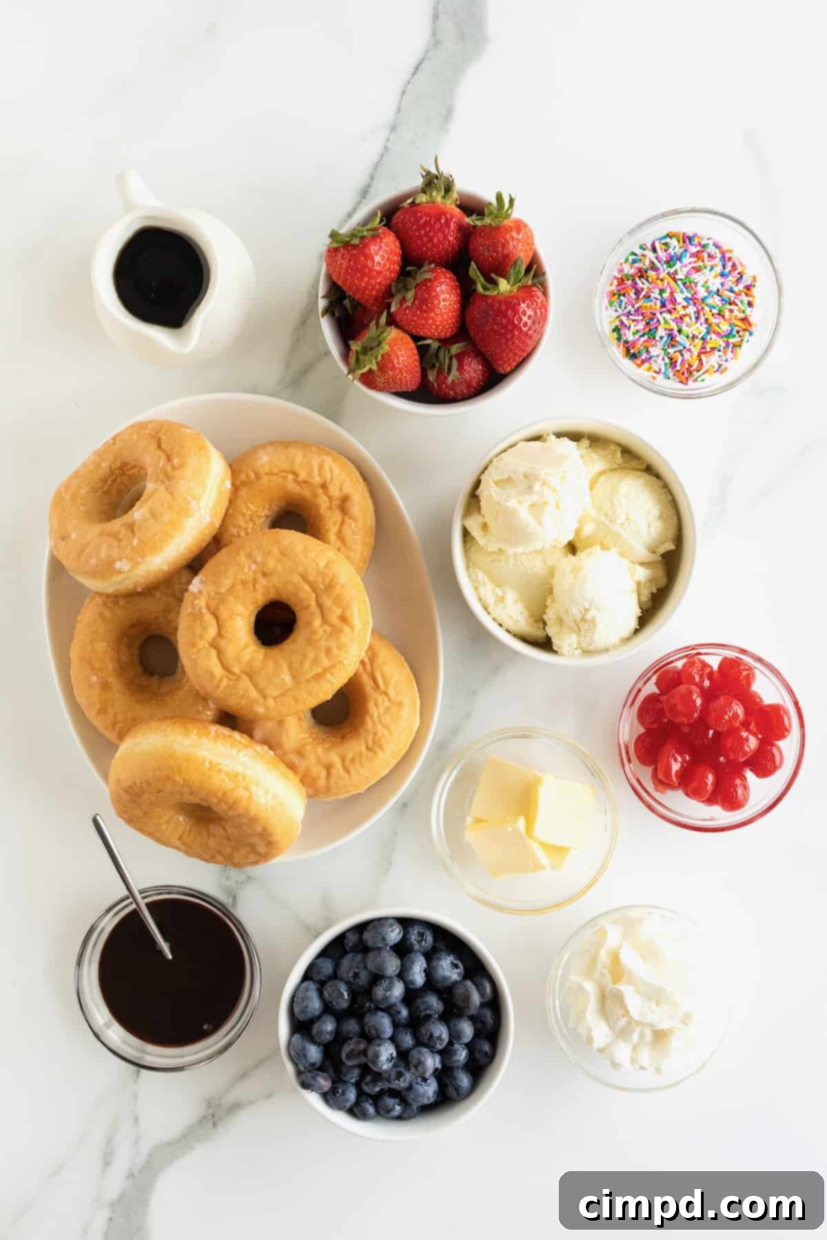 Glazed Waffle Rings 7 A flat lay of glazed donuts, fresh fruit, ice cream, and sprinkles, ready for making donut waffles and sundaes.