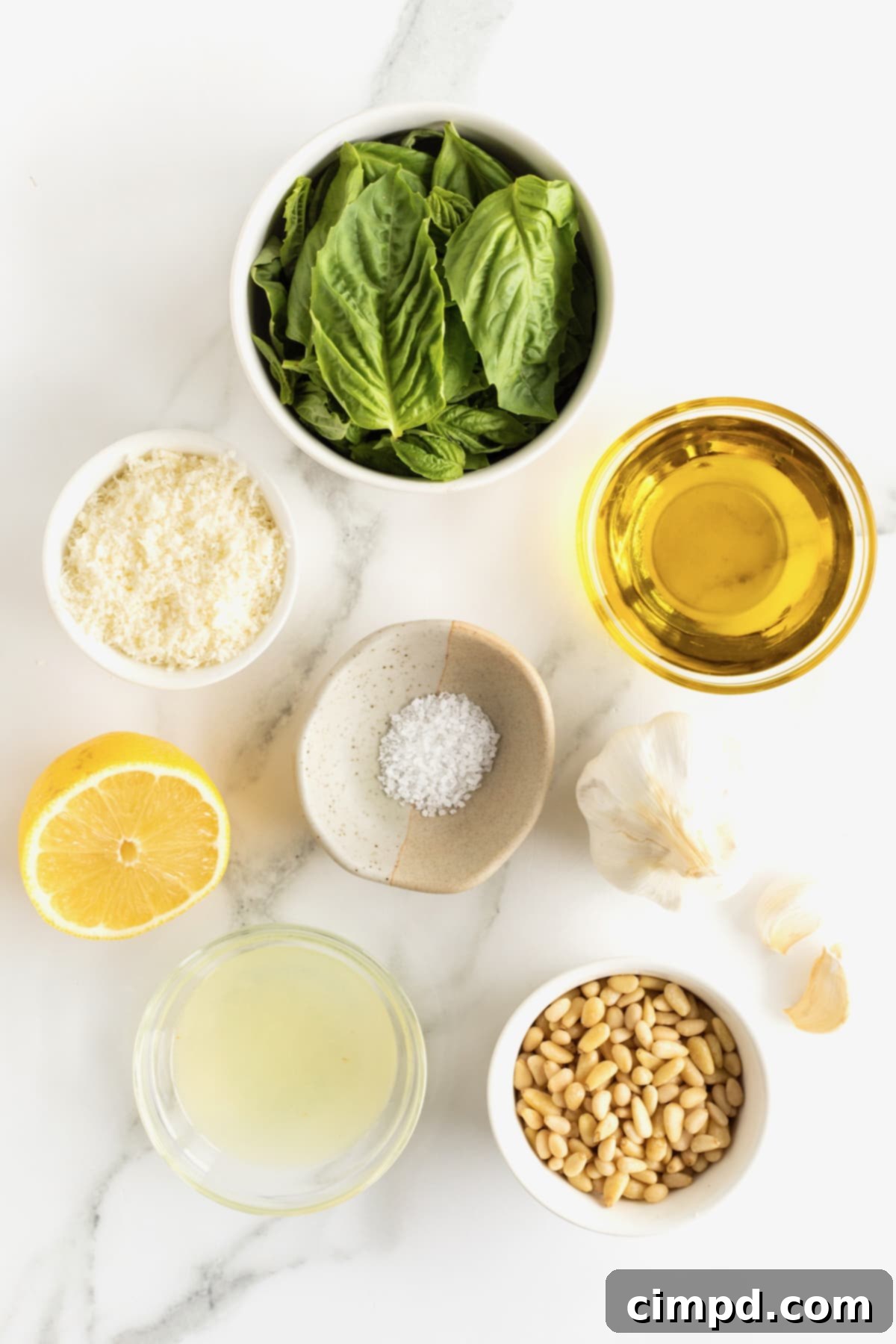 Crafting Your Own Fresh Basil Pesto 5 Arrangement of fresh basil leaves, pine nuts, a garlic clove, grated parmesan cheese, a halved lemon, lemon juice, salt, and olive oil in small containers, showcasing the key ingredients for pesto.