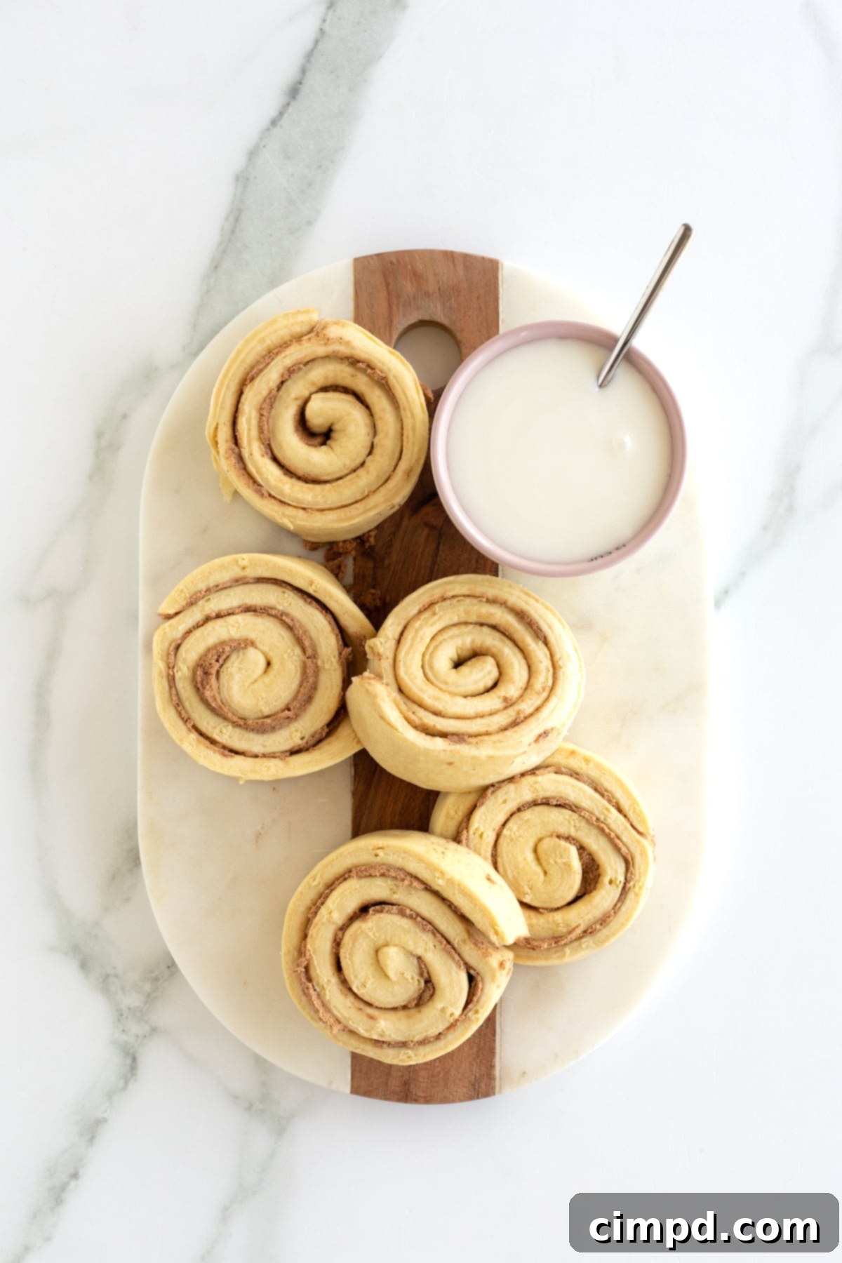 Cinnamon Swirl Pancakes 6 Store bought jumbo cinnamon rolls on a cutting board with the icing on the side.