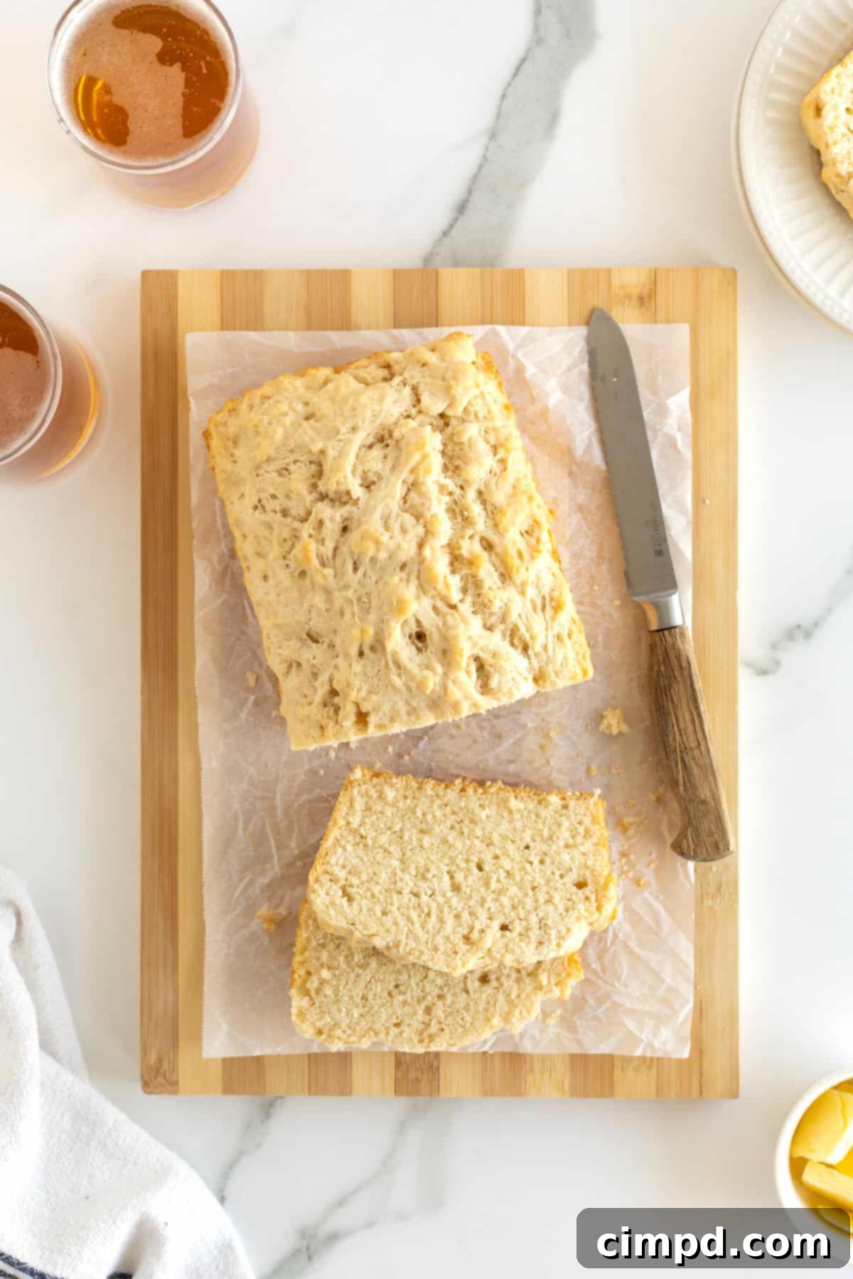 Pub-Style Beer Bread 12 A beautiful loaf of beer bread, expertly cut into thick slices and presented on a parchment-lined wooden cutting board, ready for serving.