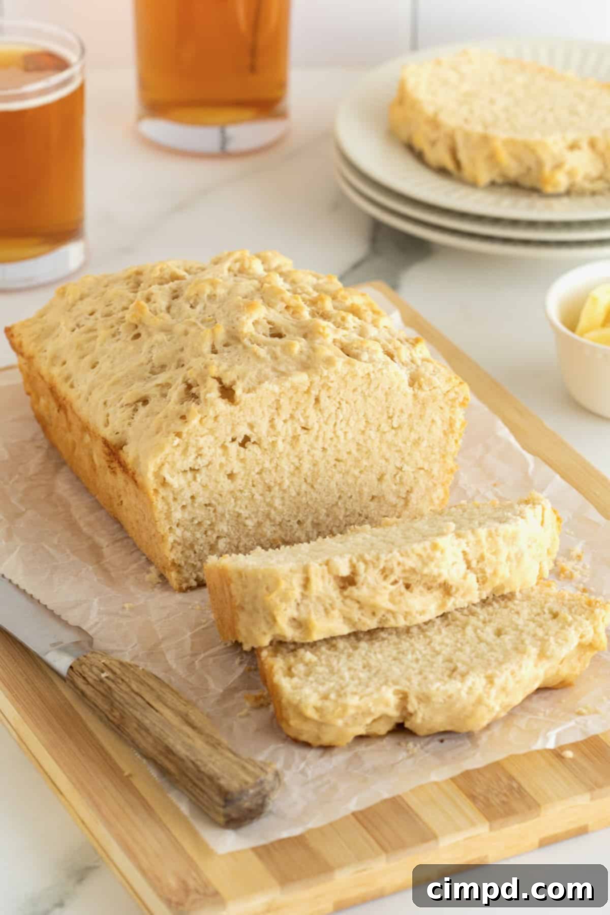 Pub-Style Beer Bread 4 A freshly baked loaf of beer bread, perfectly sliced and arranged on a parchment-lined wooden cutting board.