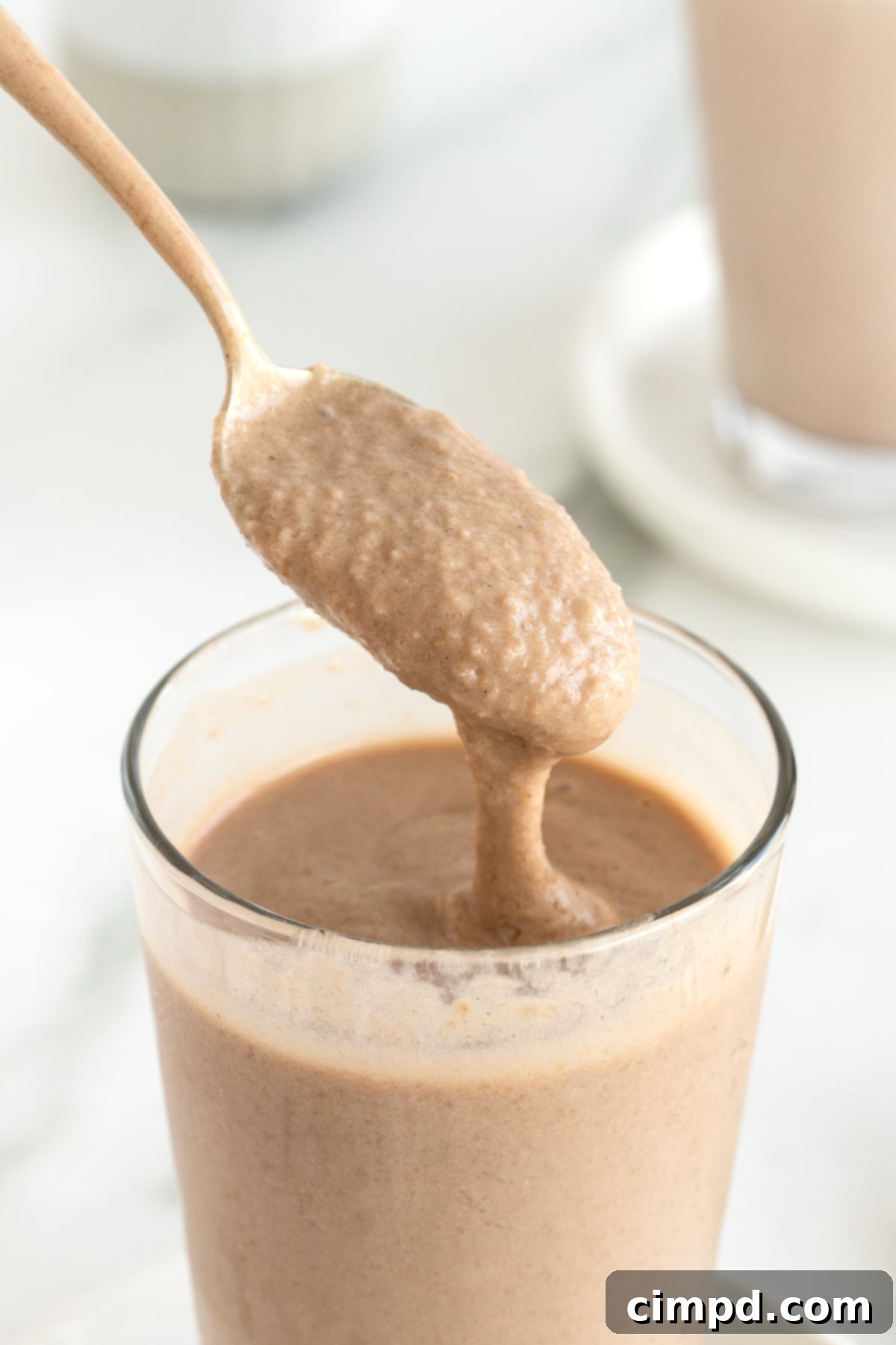 A spoon resting in a clear glass filled with a homemade Wendy's frosty, showcasing its rich texture and inviting appearance.