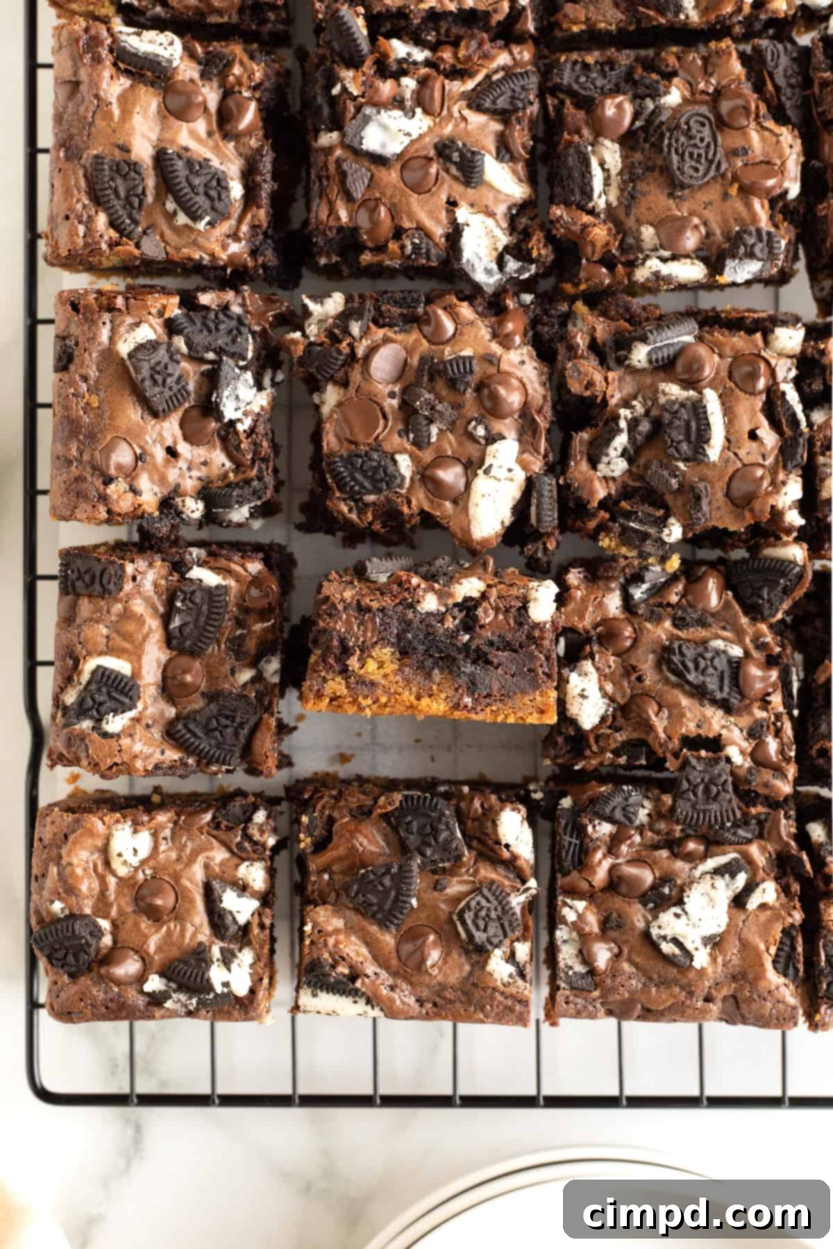 A final arrangement of nine perfect triple-layer brownies on a parchment-lined cooling rack.