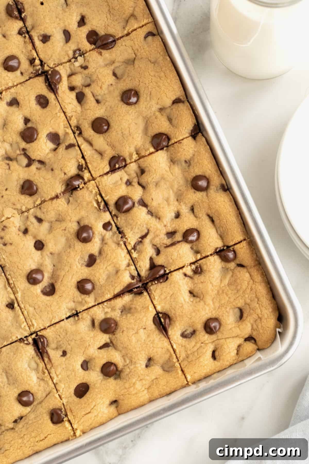 An aluminum sheet pan of peanut butter chocolate chip cookies cut into squares.