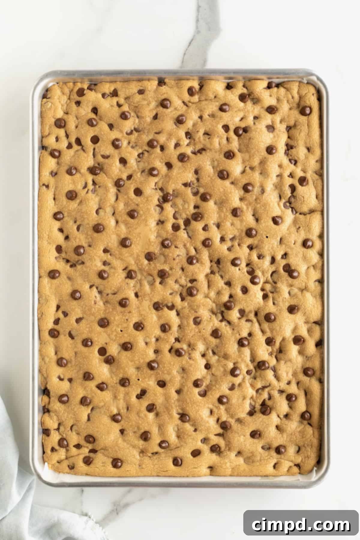 A sheet pan with peanut butter chocolate chip cookie dough pressed into it.