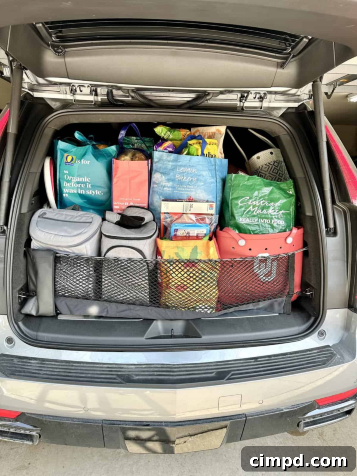 The back of an SUV packed efficiently with bags of groceries and coolers, ready for a family road trip and vacation meal prep.