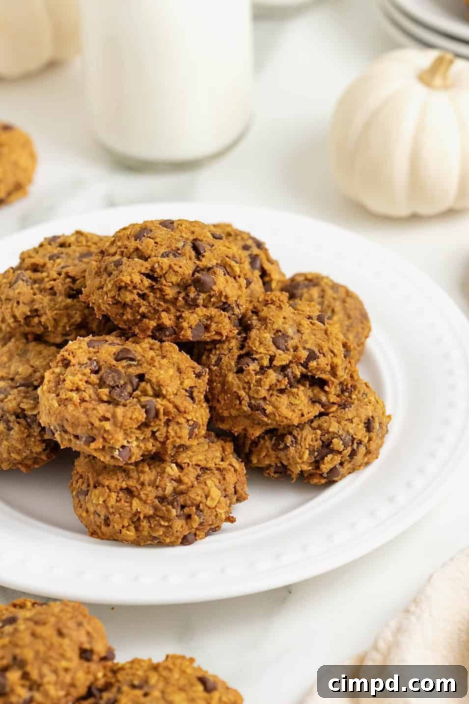 A white round serving platter of mini pumpkin chocolate chip oatmeal cookies.