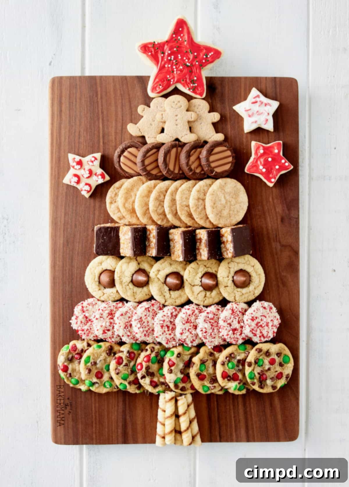 A beautifully arranged Christmas Tree Cookie Board on a wooden platter, featuring a variety of holiday cookies like sugar cookies, chocolate chip cookies, and gingerbread, topped with a bright red star cookie.