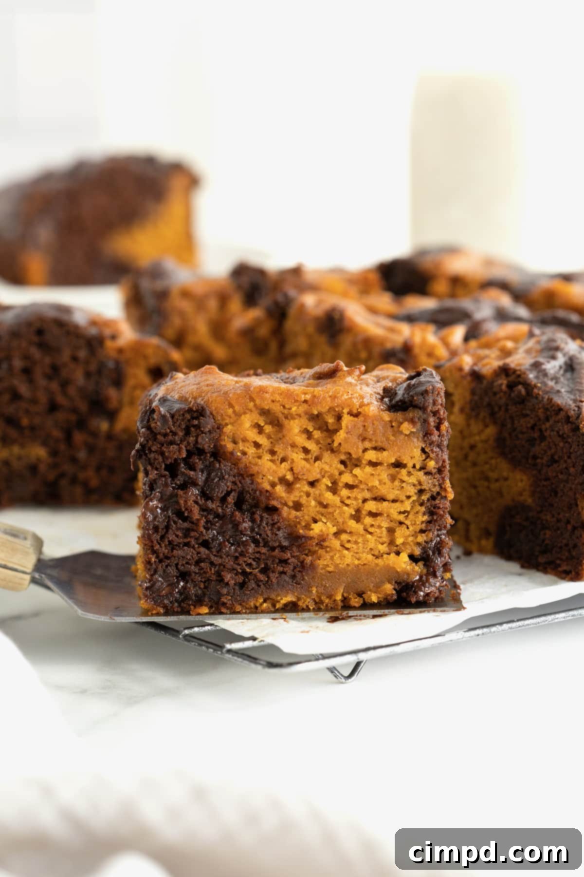 Nine pumpkin swirl brownies on a parchment lined metal cooling rack.