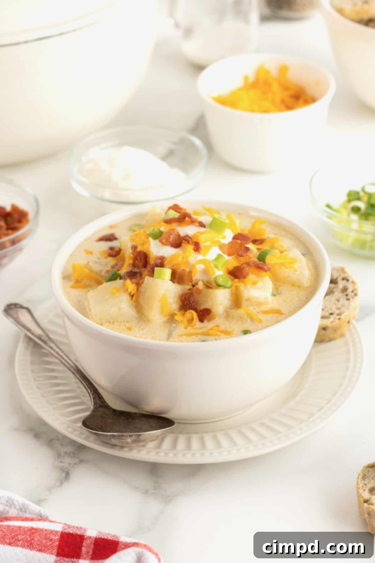 Hearty Loaded Baked Potato Soup 2 A steaming bowl of rich, creamy loaded baked potato soup, generously topped with crisp bacon bits, shredded sharp cheddar cheese, a dollop of sour cream, and freshly chopped green chives. The bowl sits on a rustic wooden table, ready to be enjoyed.