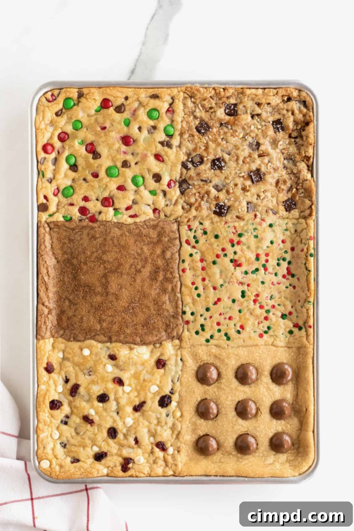 A glorious display of six different kinds of holiday cookie bars, perfectly baked and cooling within an aluminum baking sheet, showcasing their festive appeal.