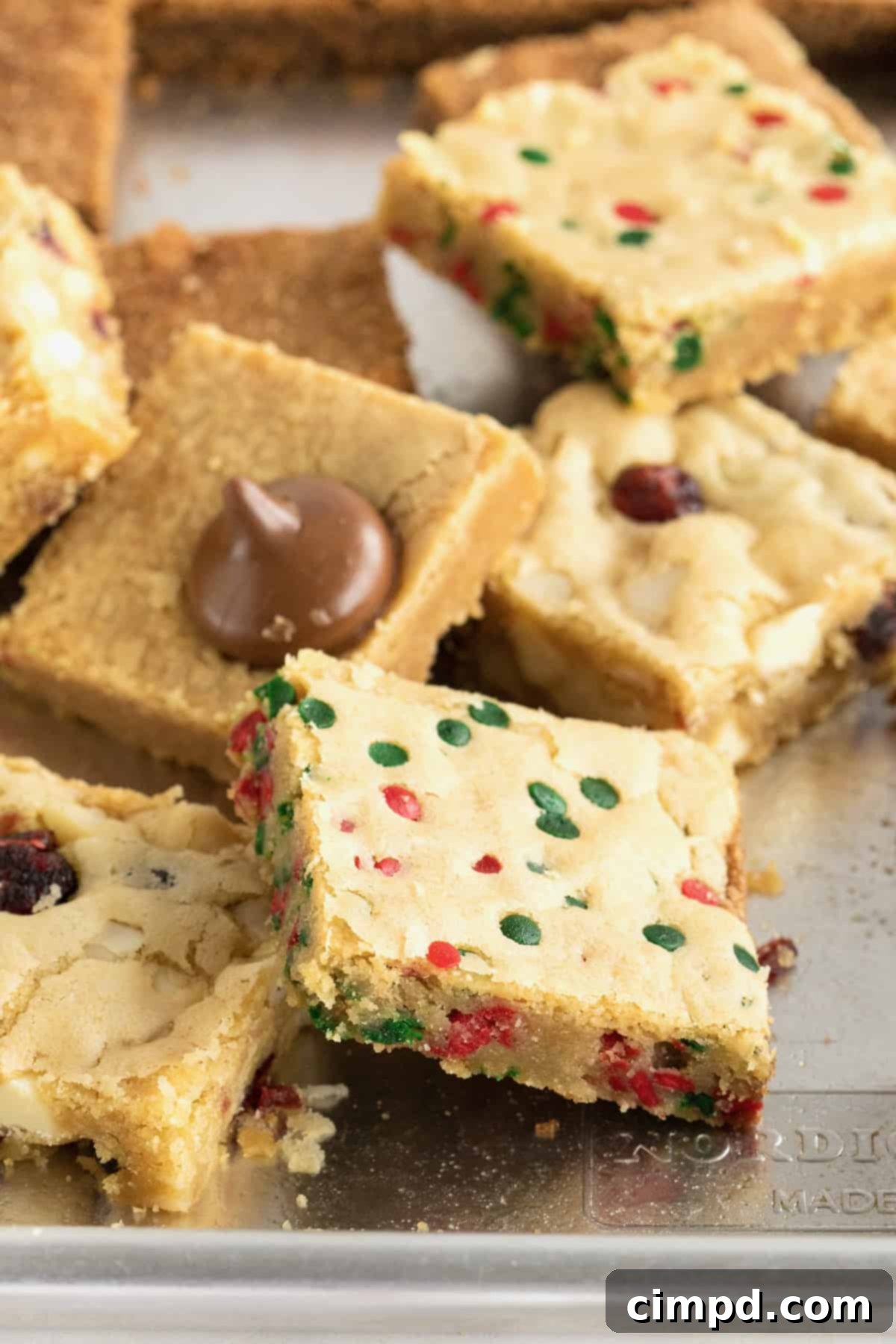 A generous pile of freshly baked holiday cookie bars resting on an aluminum baking sheet, ready for serving or storage.