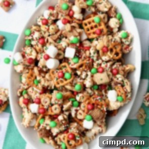An oval shaped white bowl filled with Christmas party snack mix, colorful and inviting.