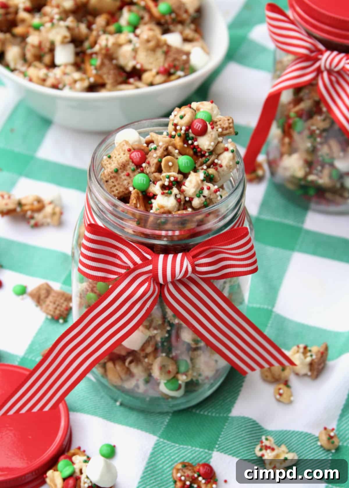 A charming jar of holiday snack mix tied with a red and white ribbon, signifying a perfect homemade gift.