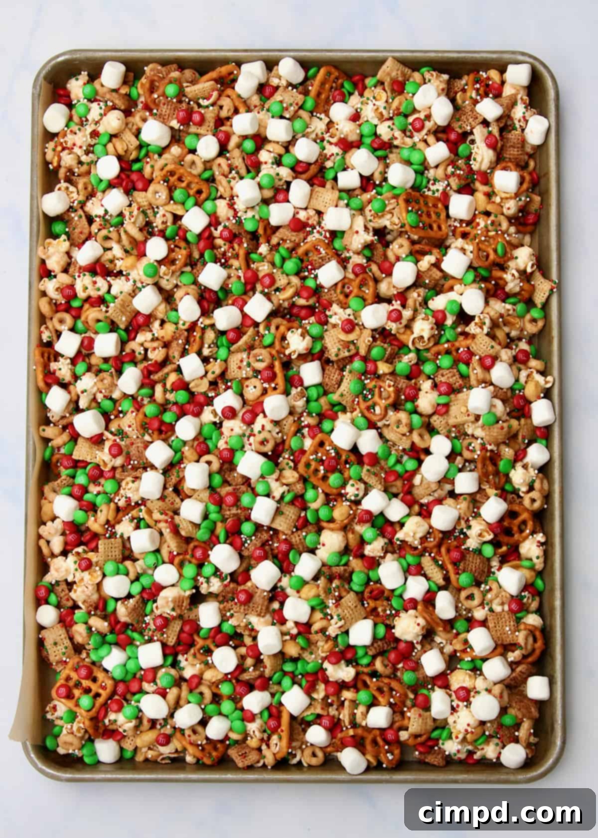 A baking tray filled with cooling snack mix, generously adorned with festive sprinkles and candies, fresh out of preparation.