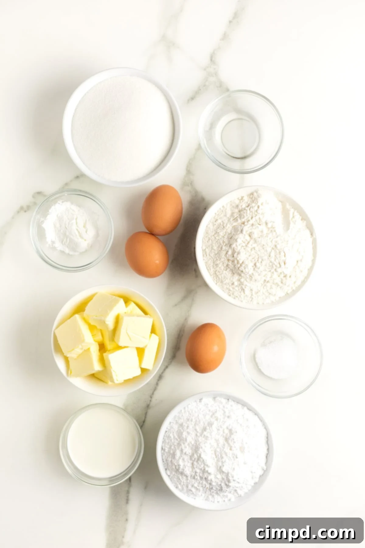 A beautiful arrangement of all the fresh ingredients required to make delicious sugar cookies, meticulously displayed in small, elegant glass dishes on a clean white kitchen counter, ready for baking.