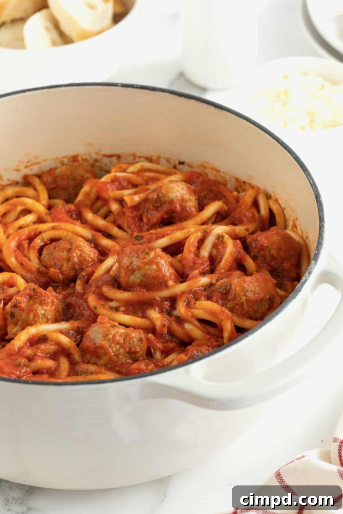 A white dutch oven filled with Spaghetti and Meatballs.