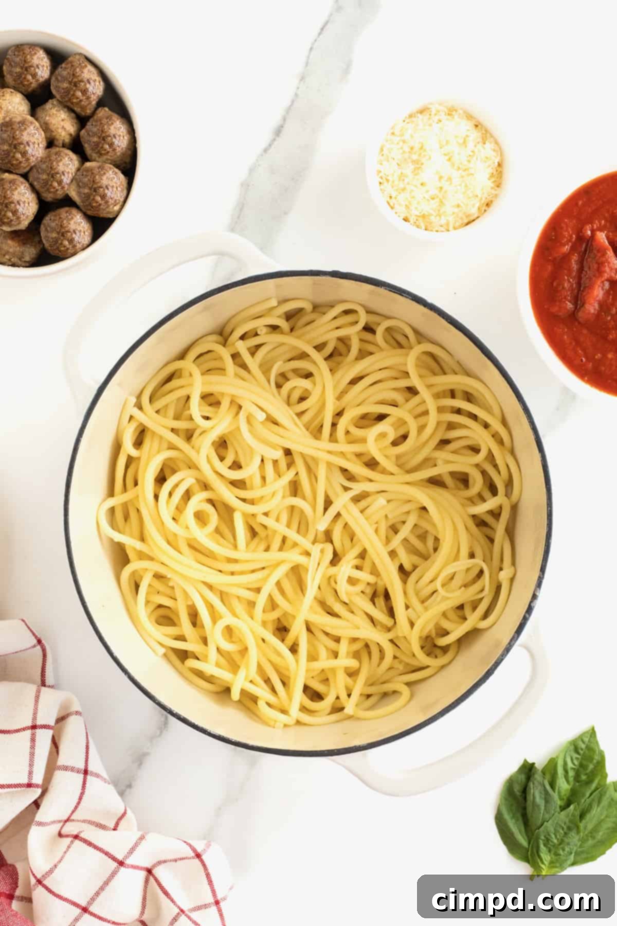 A large white dutch oven full of long thin noodles.