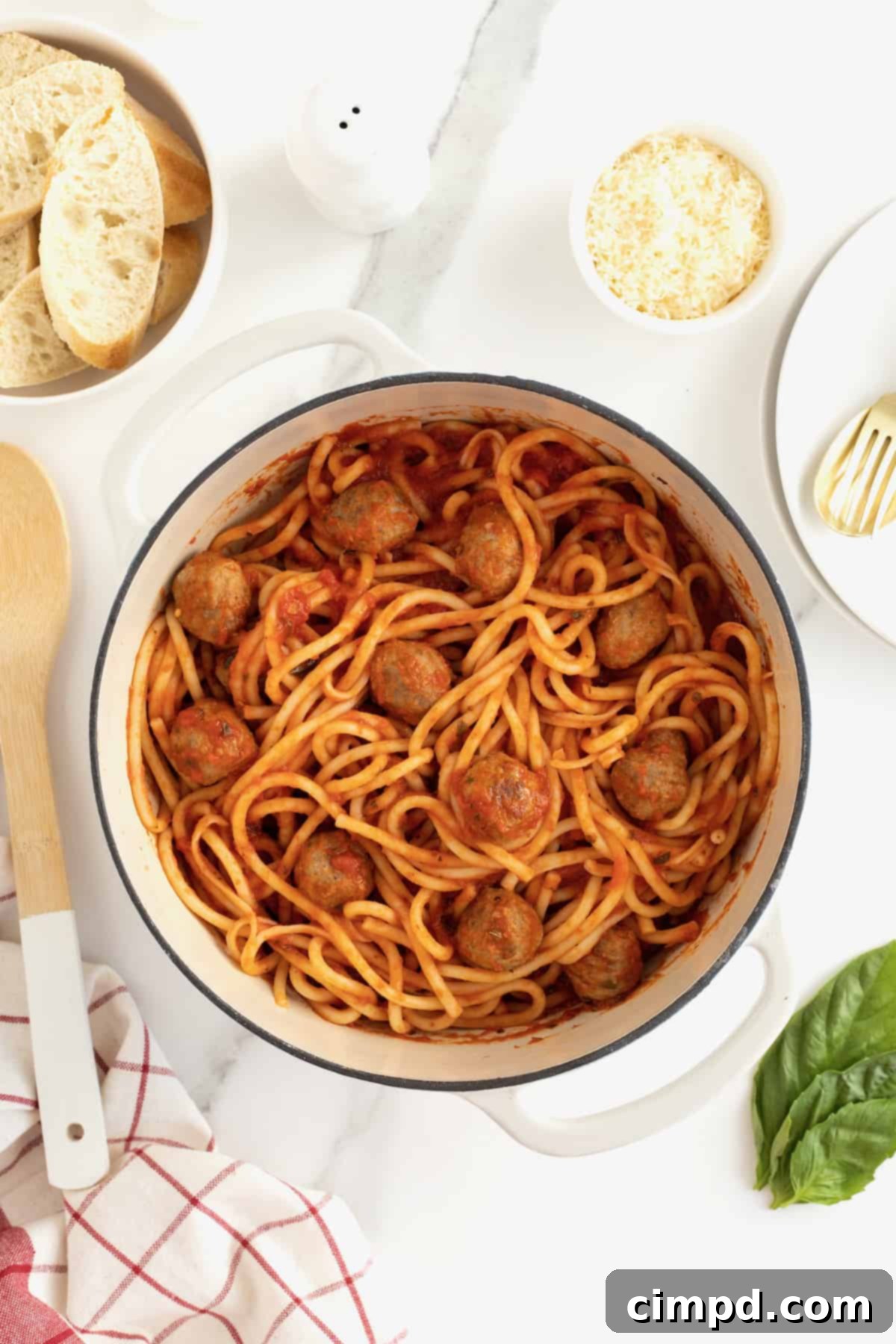 A white dutch oven filled with Spaghetti and Meatballs.