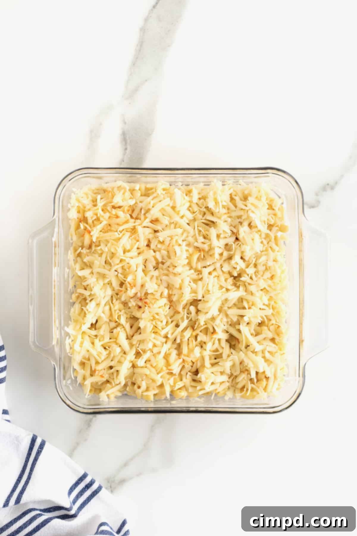 Creamy Muenster Mac and Cheese 9 A square glass dish filled with macaroni and cheese, generously topped with a layer of shredded Muenster cheese.