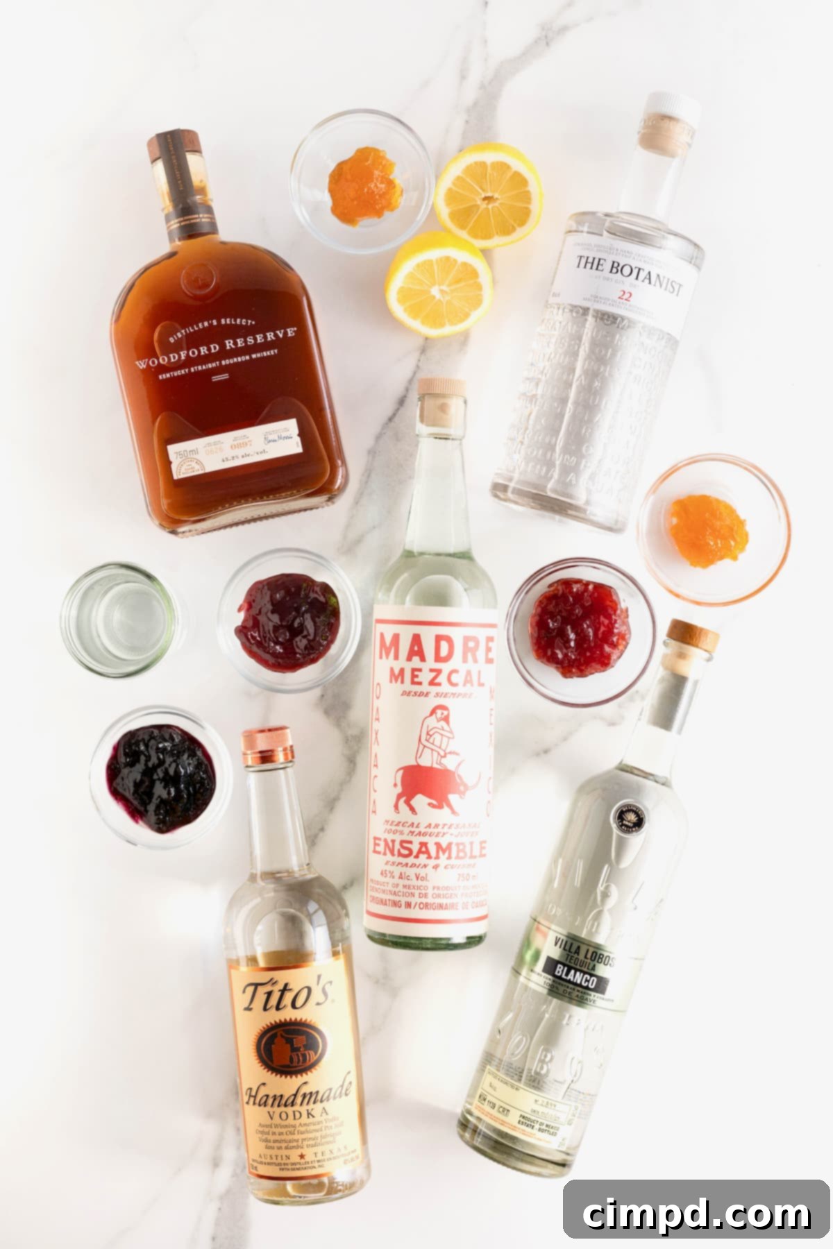 An array of liquor bottles and small glass jars of various fruit jams displayed on a pristine white marble counter, ready for cocktail creation.