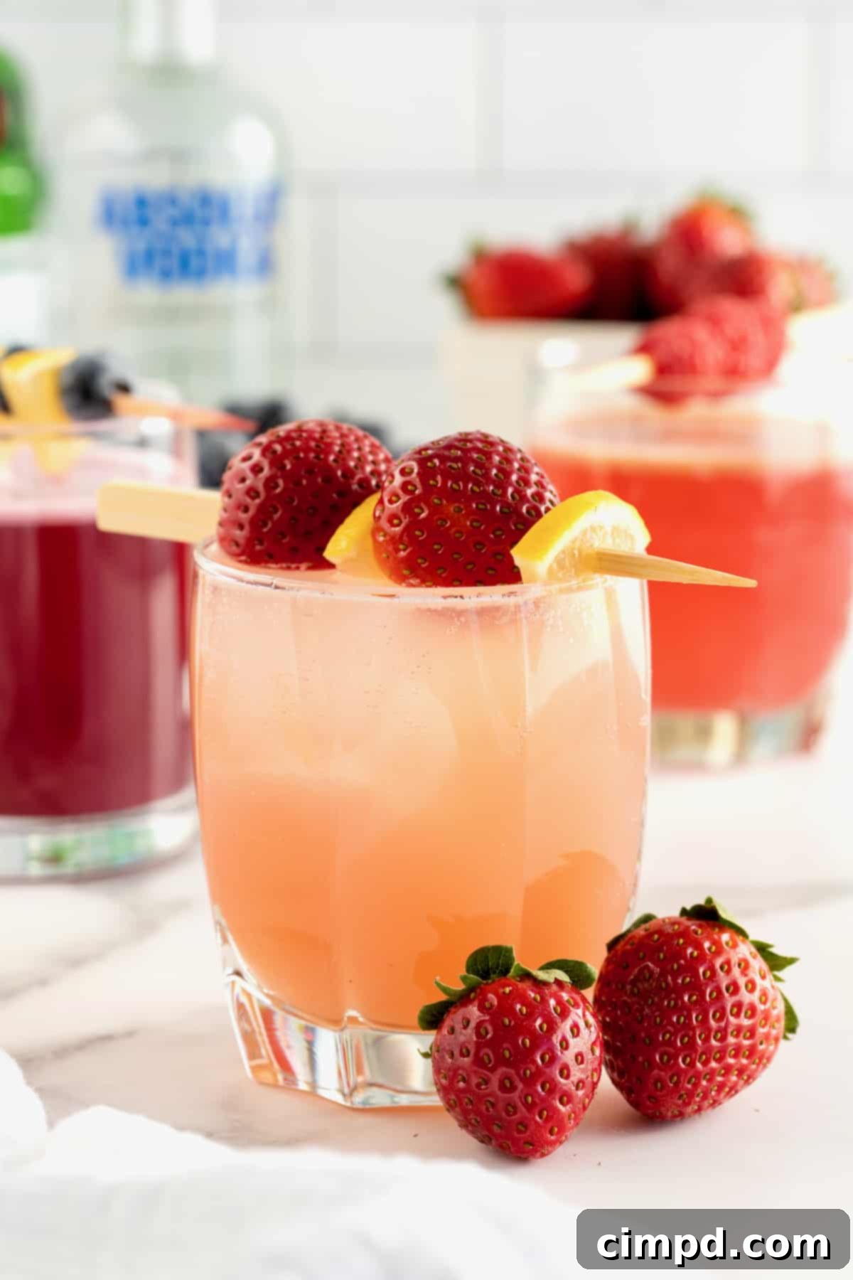 A perfectly crafted pink cocktail in a short glass, beautifully garnished with a wooden toothpick holding whole strawberries and thinly sliced lemon.