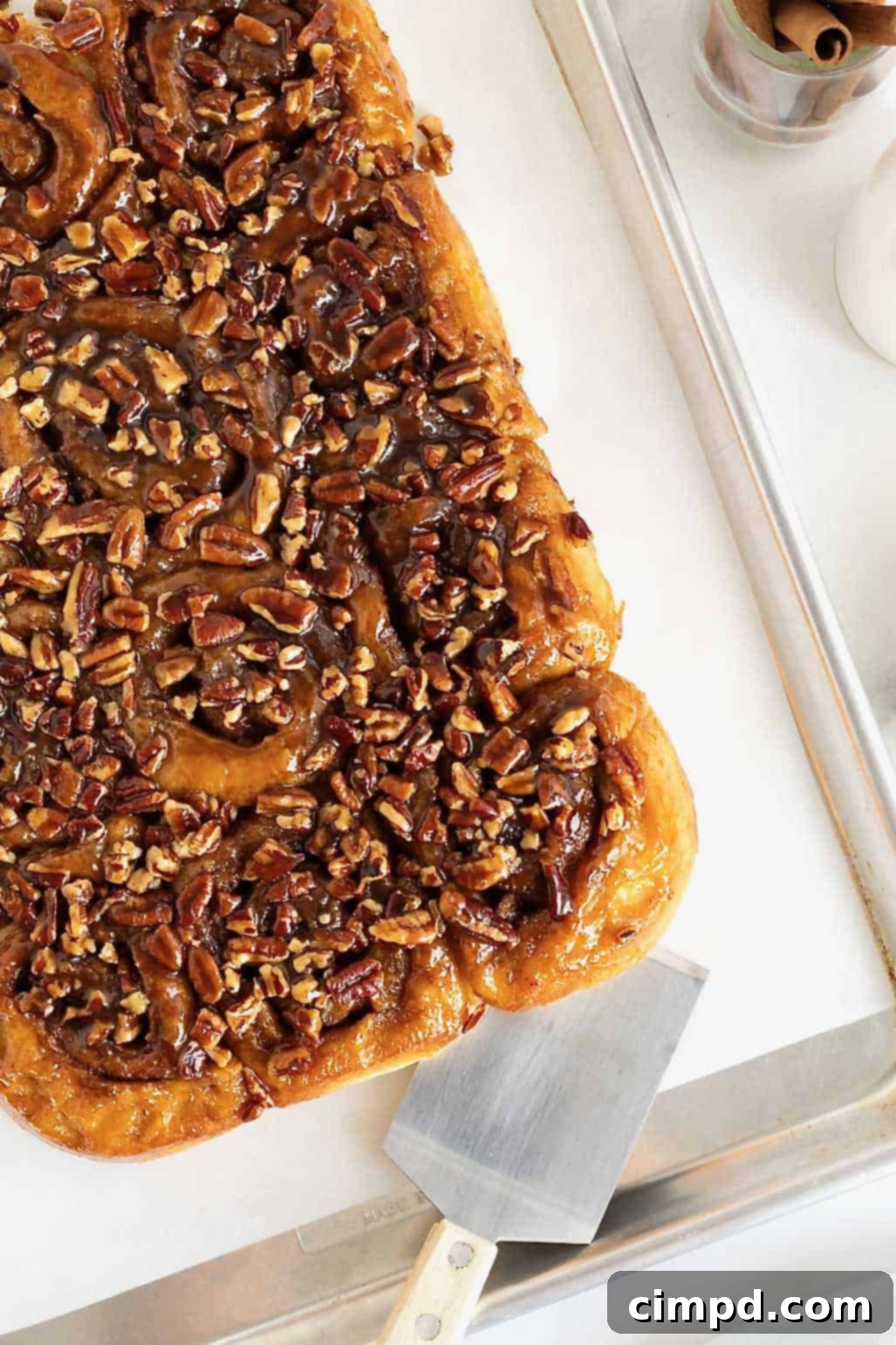 Sticky buns on a parchment lined aluminum baking sheet.