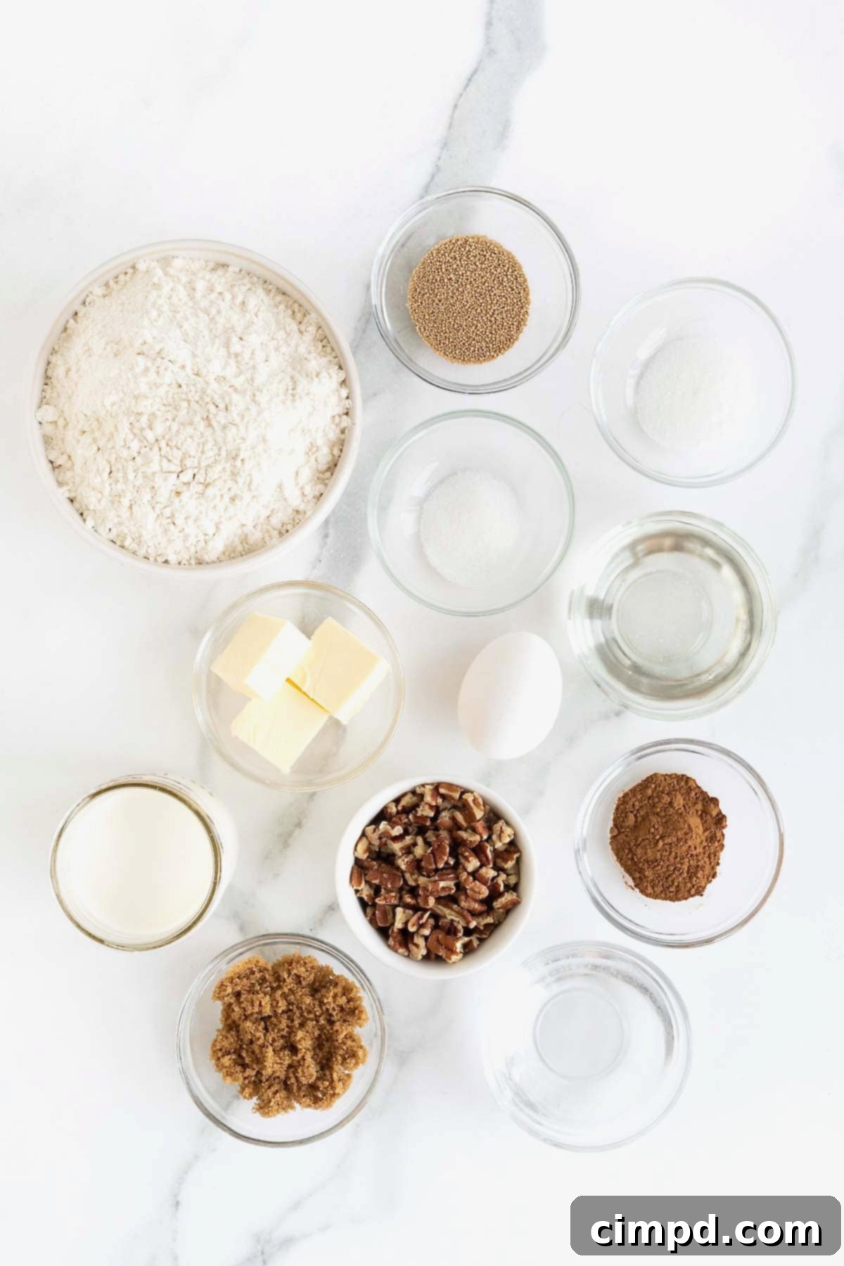 Ingredients to make sticky buns in small glass dishes on a white marble counter.