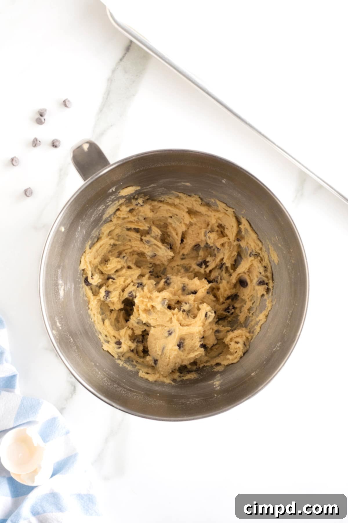 The Ultimate Chocolate Chip Cookies 8 Rich chocolate chip cookie dough rests invitingly in the gleaming bowl of a stainless steel stand mixer, ready for scooping.