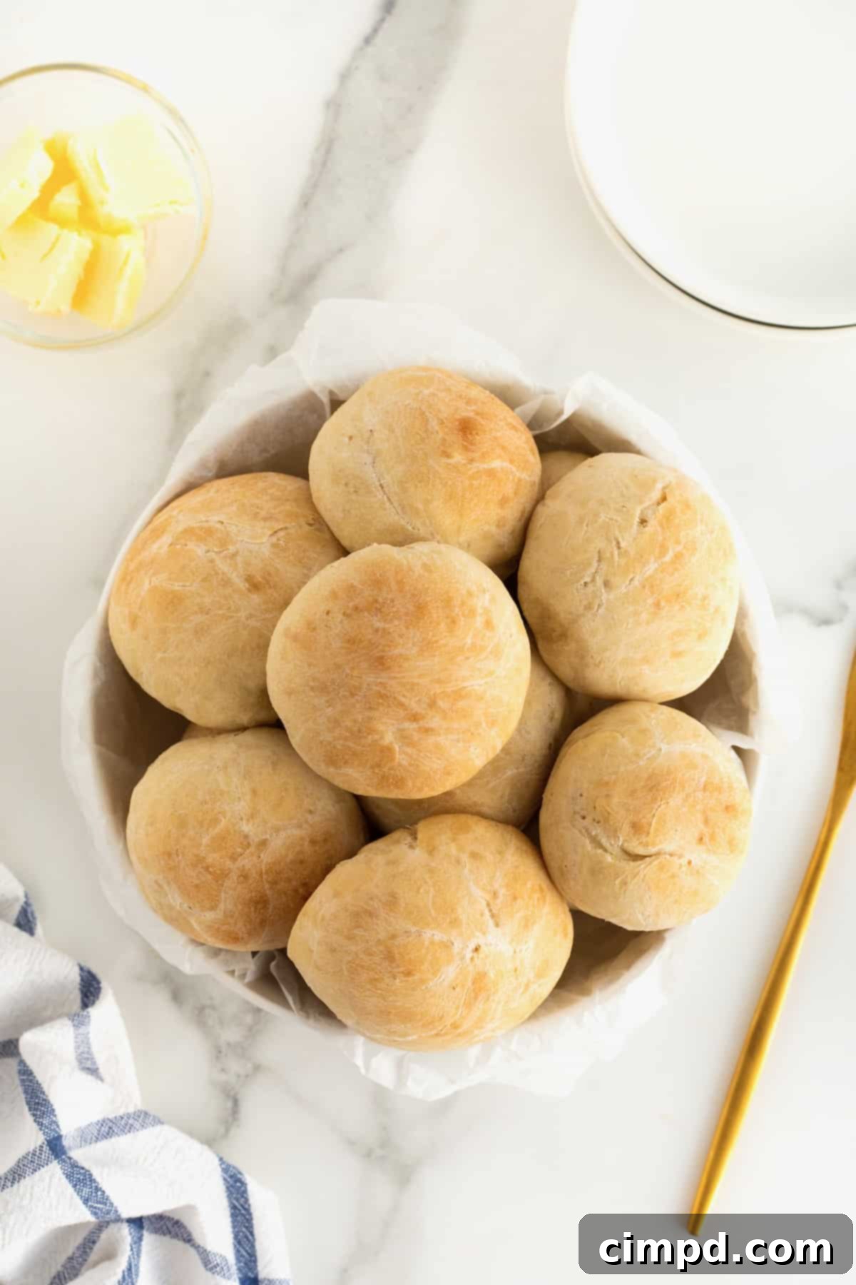 Traditional Dinner Rolls 9 Nine warm, round dinner rolls are artfully arranged in a rustic white serving bowl, ready for the table, suggesting comfort and homemade goodness.