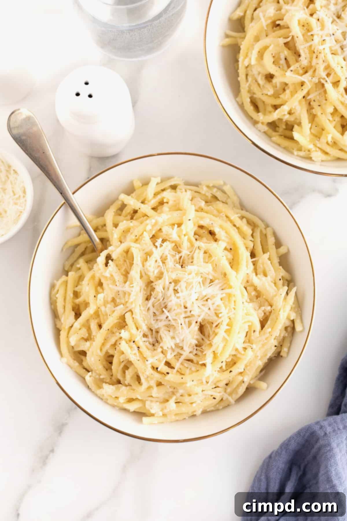 A large white, gold-rimmed serving bowl brimming with Cacio e Pepe, ready to be enjoyed.