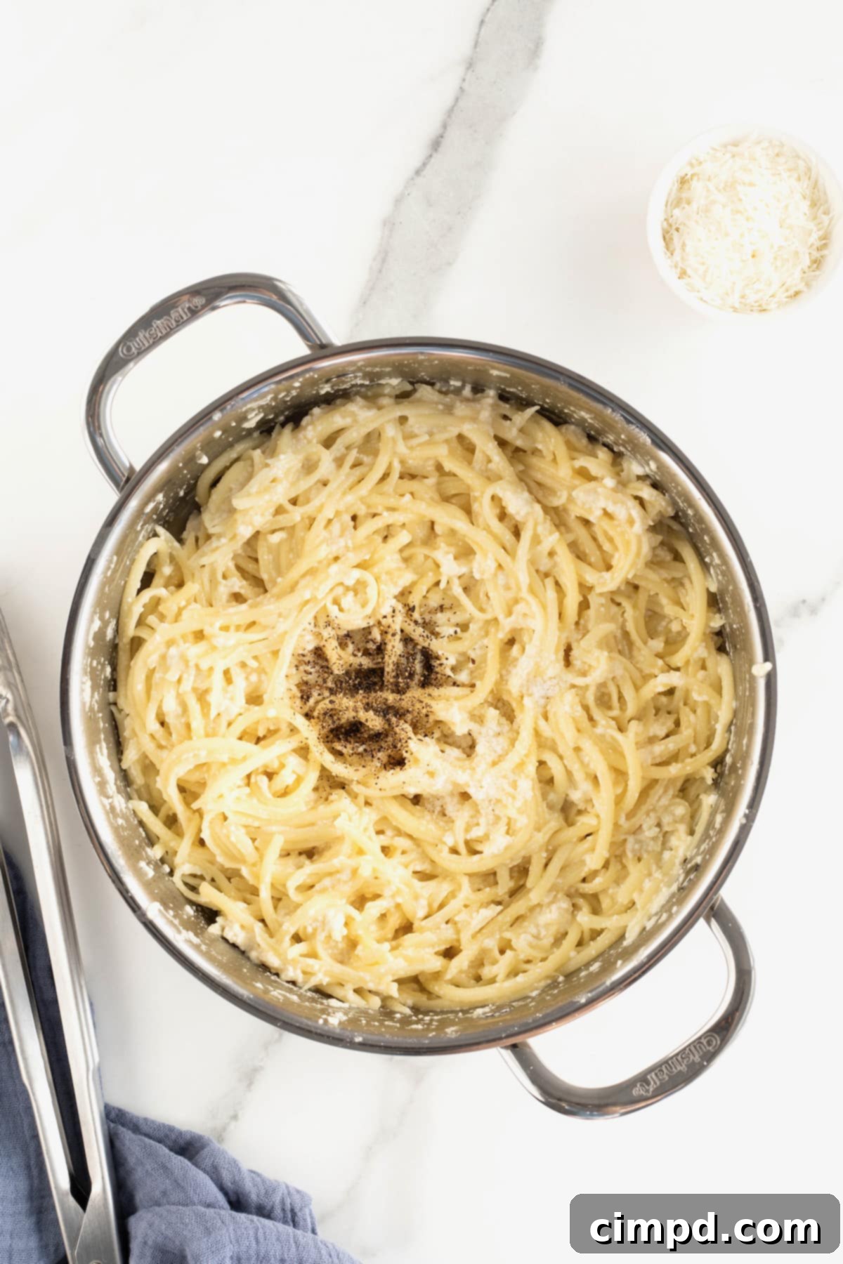Fresh black pepper being added to a pot of creamy Cacio e Pepe, emphasizing the key seasoning.