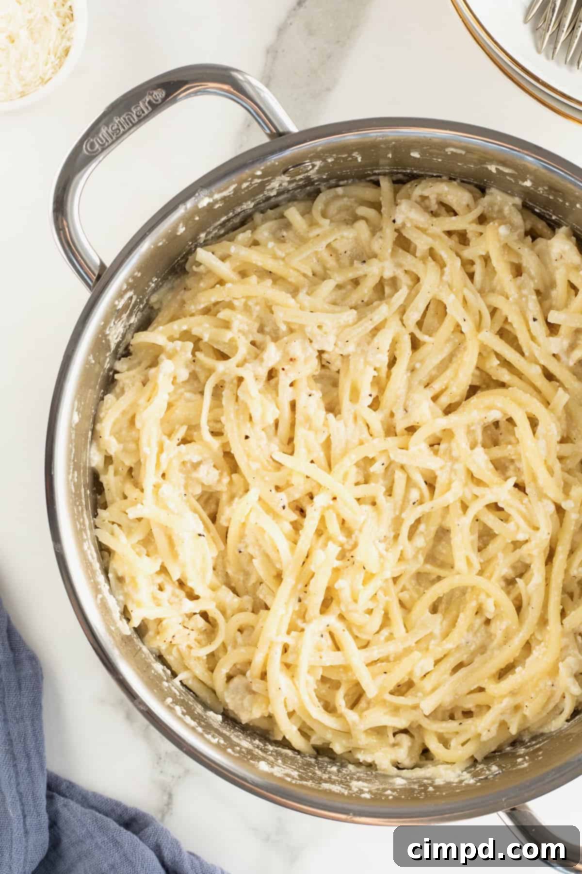 A large stainless steel pot full of perfectly cooked Cacio e Pepe, showcasing its rich, creamy texture.