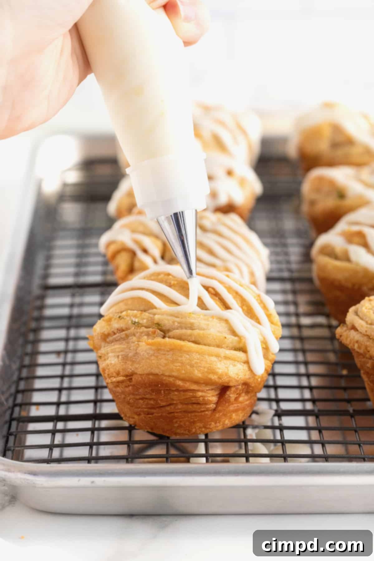 Close-up shot of Key Lime icing being piped artfully onto a freshly baked cruffin, showing the smooth texture of the icing.