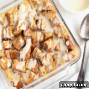 A square glass baking dish of bread pudding with white icing drizzled on top.