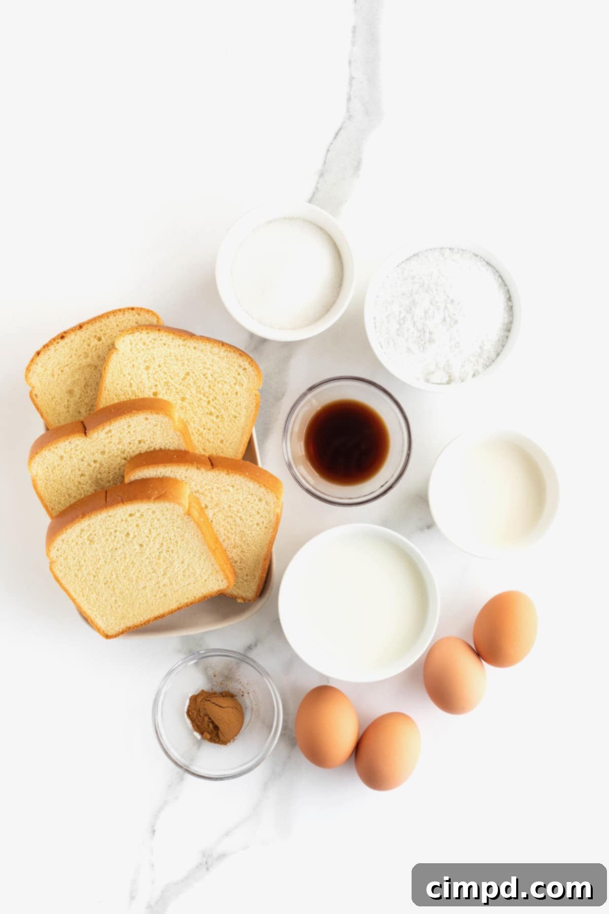 Ingredients to make bread pudding in small glass dishes on a white marble counter.