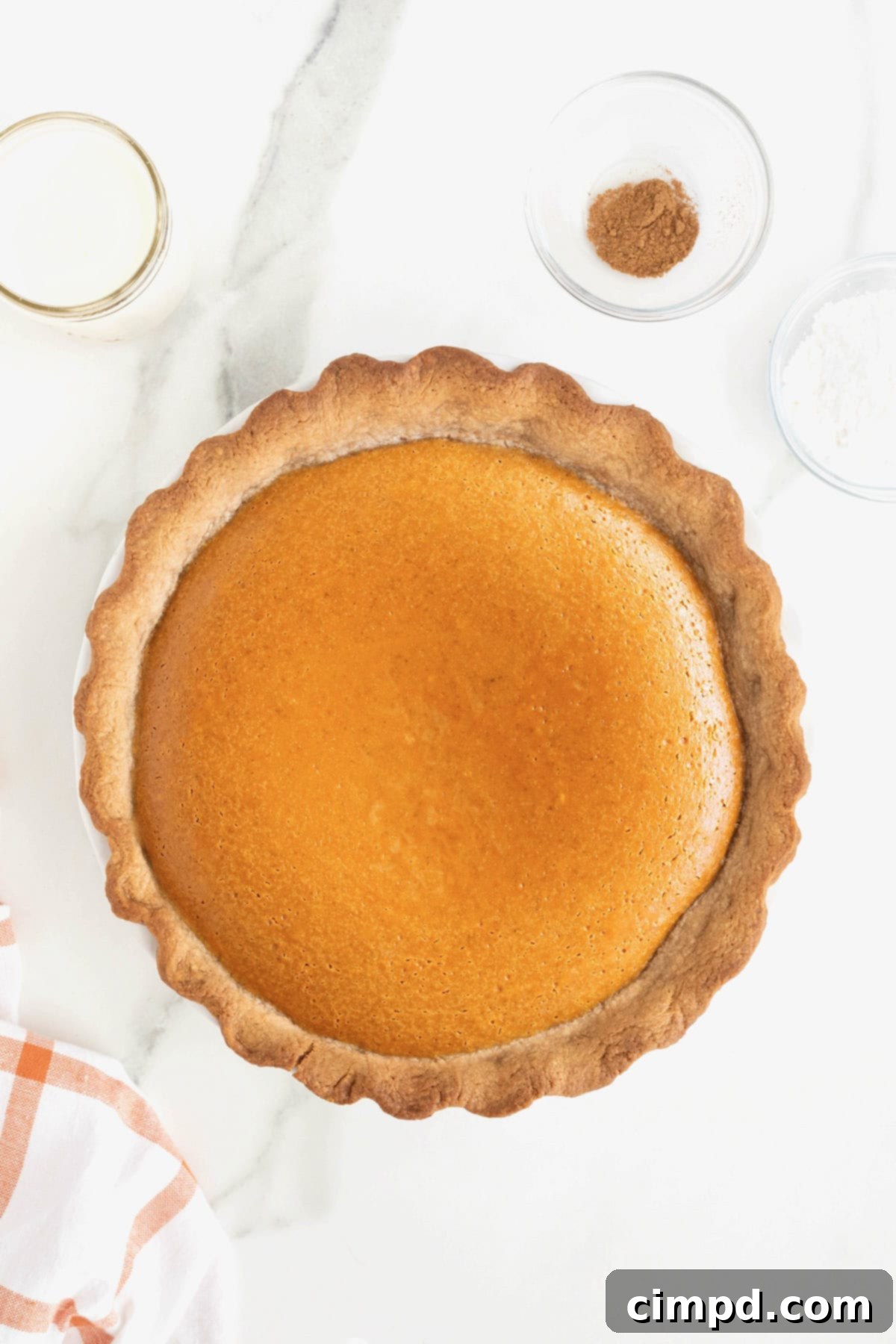 A baked pumpkin cream pie on a white marble counter.
