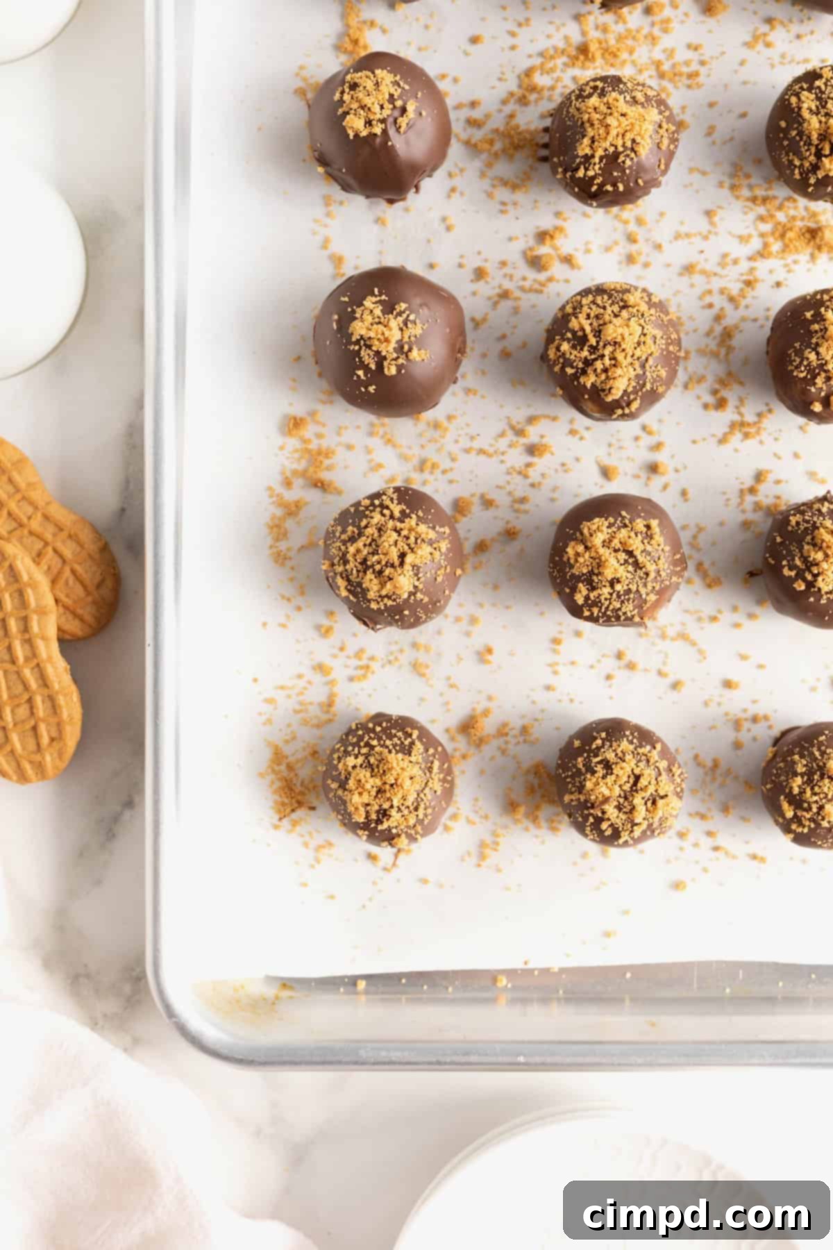 Nine perfectly formed Nutter Butter balls arranged neatly on a parchment-lined aluminum baking sheet, ready for storage or chilling.
