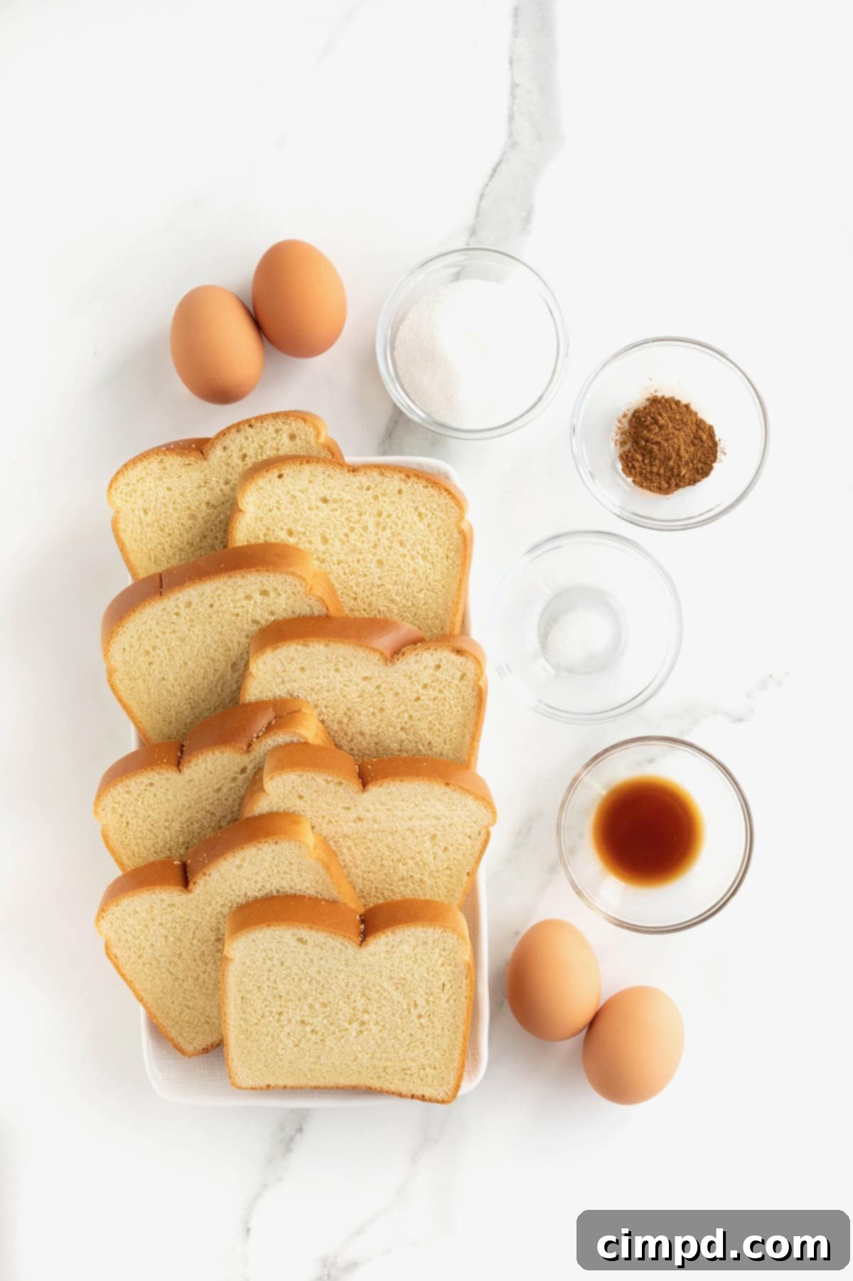 Ingredients to make baked French toast on a white marble counter.