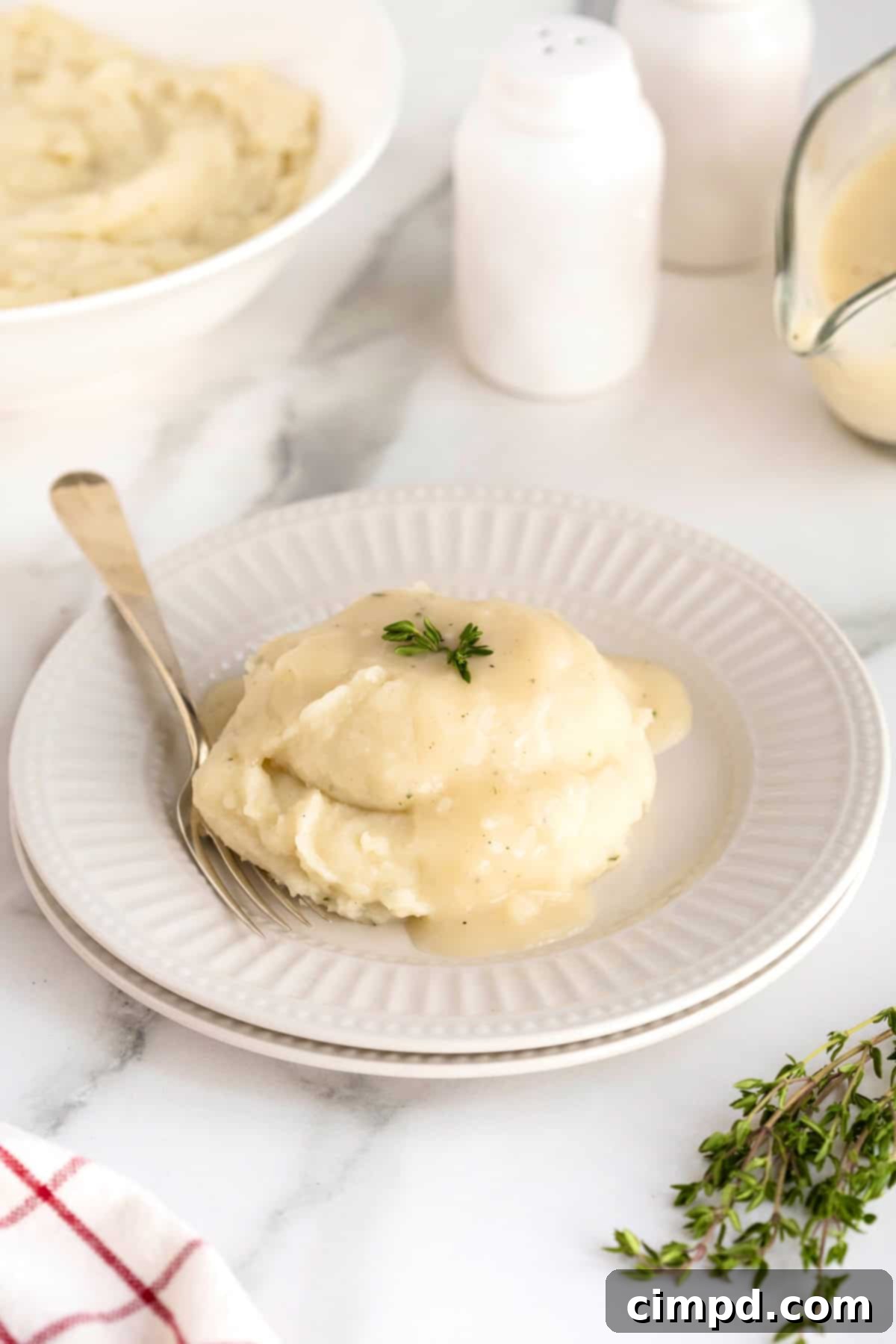 Golden-brown turkey gravy generously poured over a serving of fluffy mashed potatoes in a fluted white shallow bowl, ready to be enjoyed.