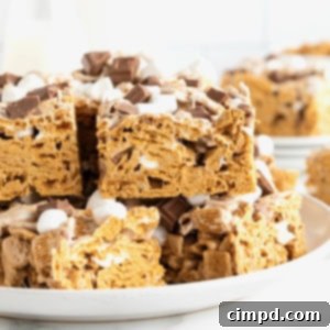 Easy No Bake Smores Bars 11 A large white rimmed plate stacked with golden brown No-Bake S'mores Bars.