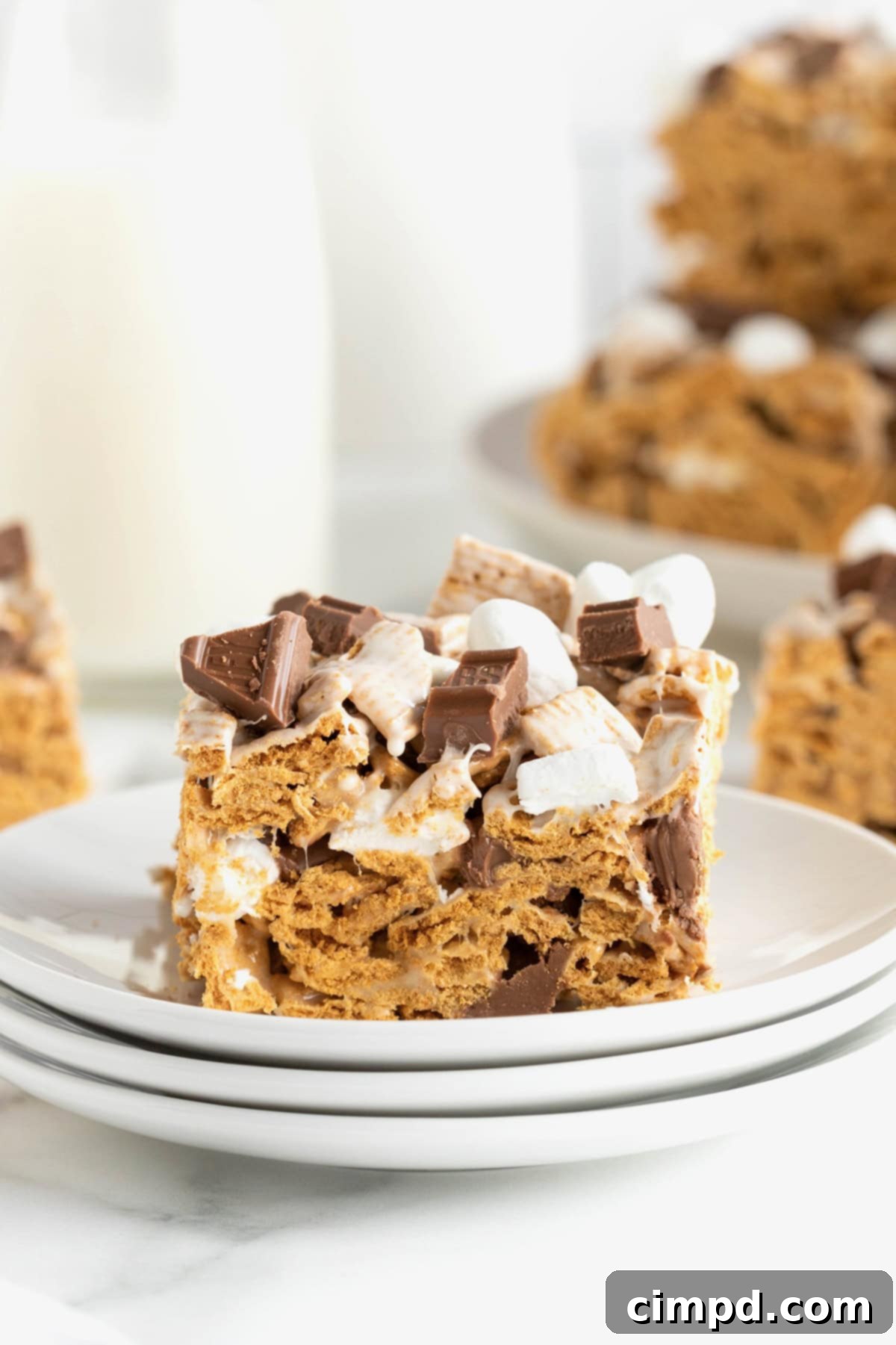 Easy No Bake Smores Bars 3 A single No-Bake S'mores Bar rests on a small stack of white dessert plates, highlighting its inviting layers.