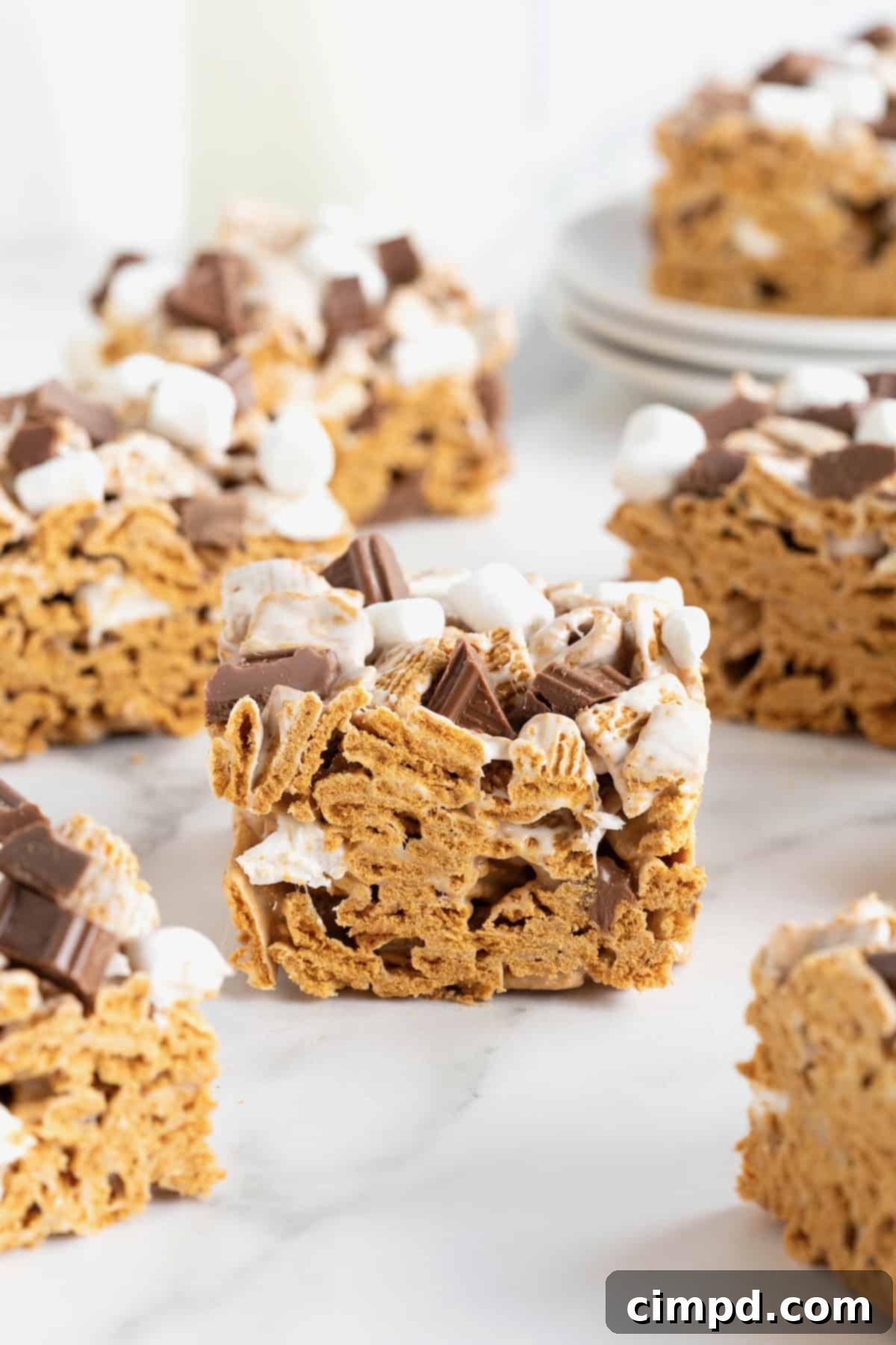 Easy No Bake Smores Bars 5 A side view of seven perfectly cut No-Bake S'mores Bars arranged neatly on a white marble counter, showcasing their layered texture.