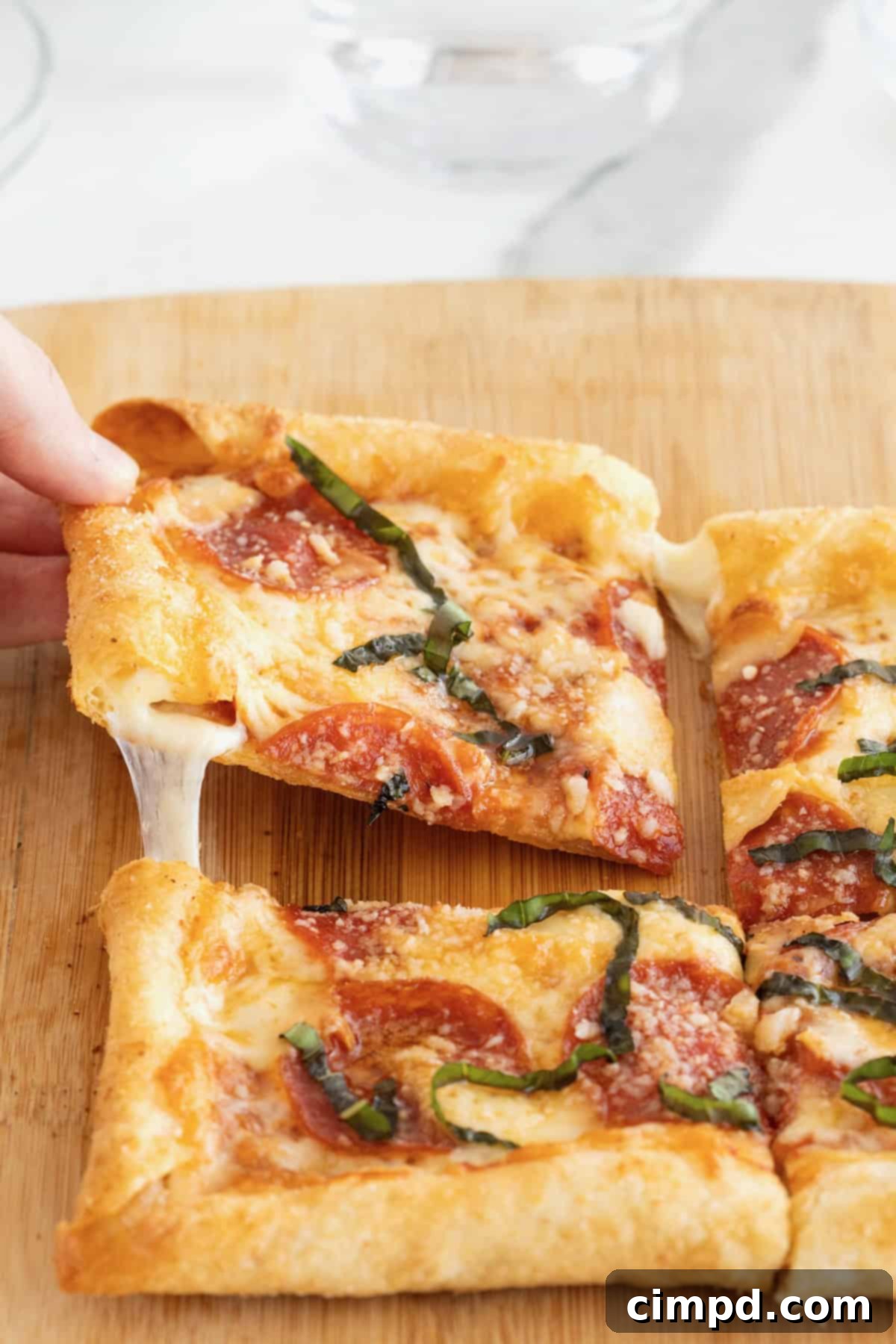 Tortilla Pizza with Stuffed Crust 2 A hand pulling a slice of pepperoni stuffed crust tortilla pizza away from the whole pizza.