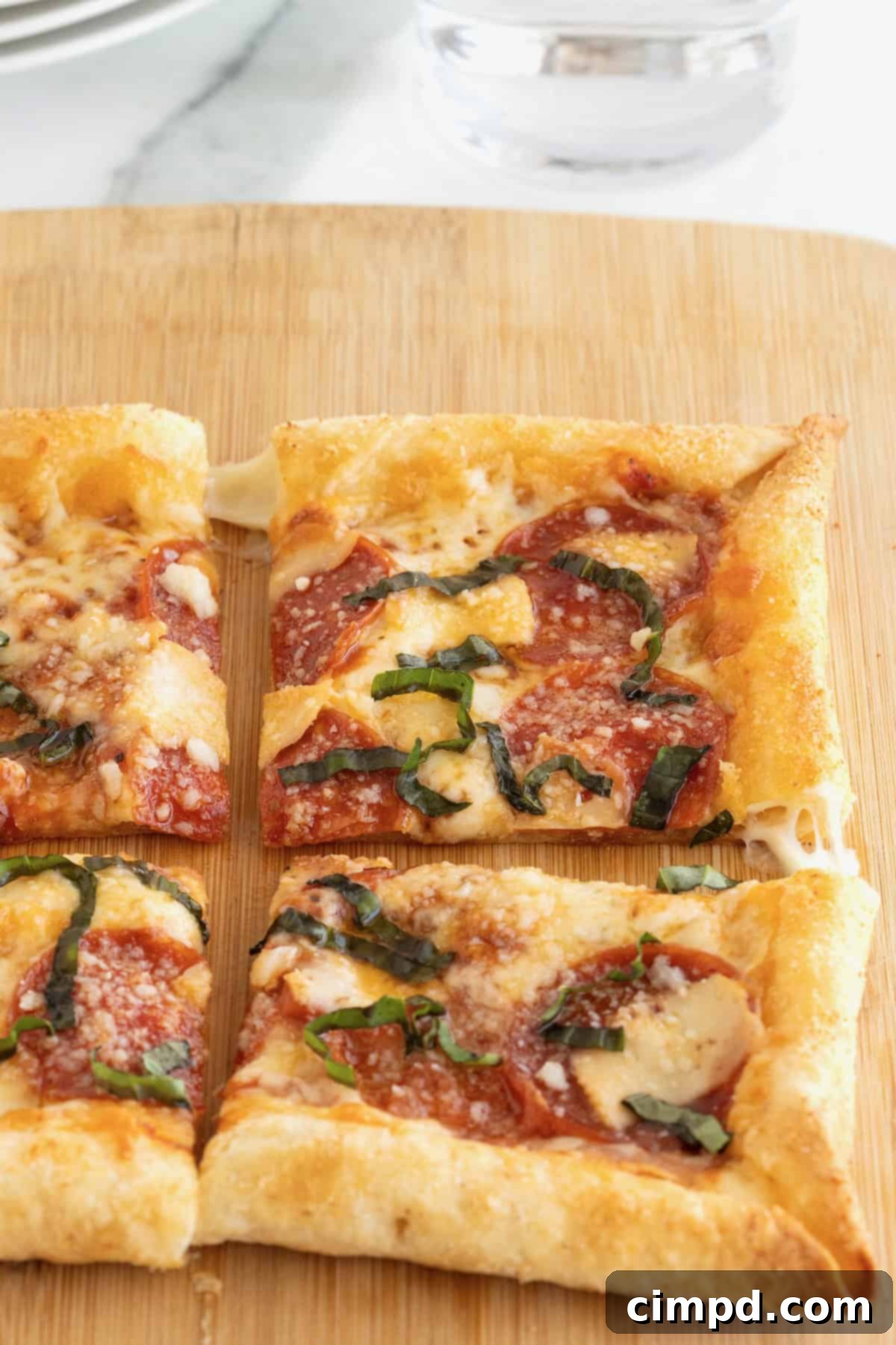 Tortilla Pizza with Stuffed Crust 10 A stuffed crust tortilla pizza cut into four pieces on a rectangular light wood cutting board.