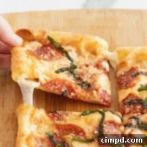Tortilla Pizza with Stuffed Crust 12 A hand pulling a slice of pepperoni stuffed crust tortilla pizza away from the whole pizza.
