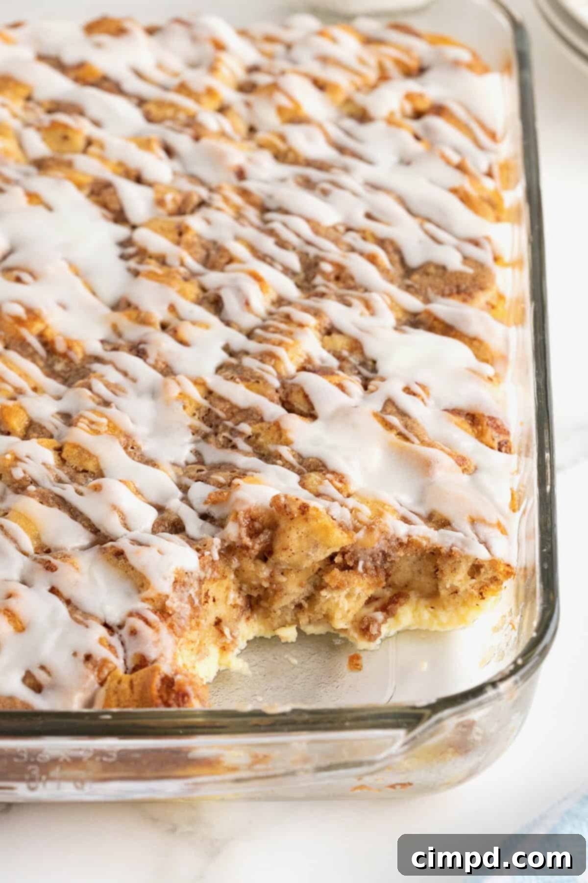 A 9x13 glass casserole dish with cinnamon roll breakfast casserole drizzled with icing.