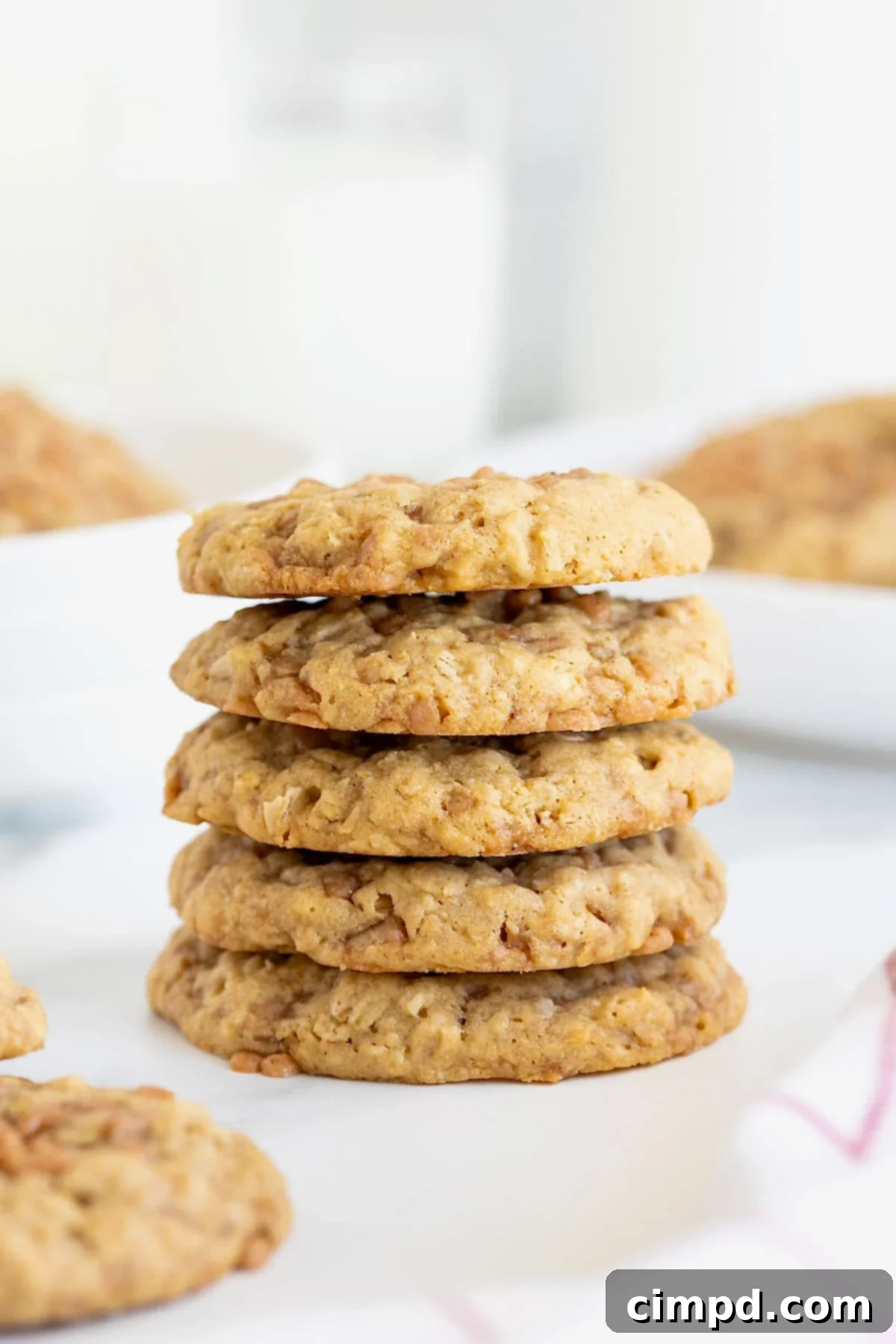 A pristine stack of five Brown Sugar Oatmeal Toffee Crunch Cookies rests on a elegant white marble counter, showcasing their golden edges and inviting texture.